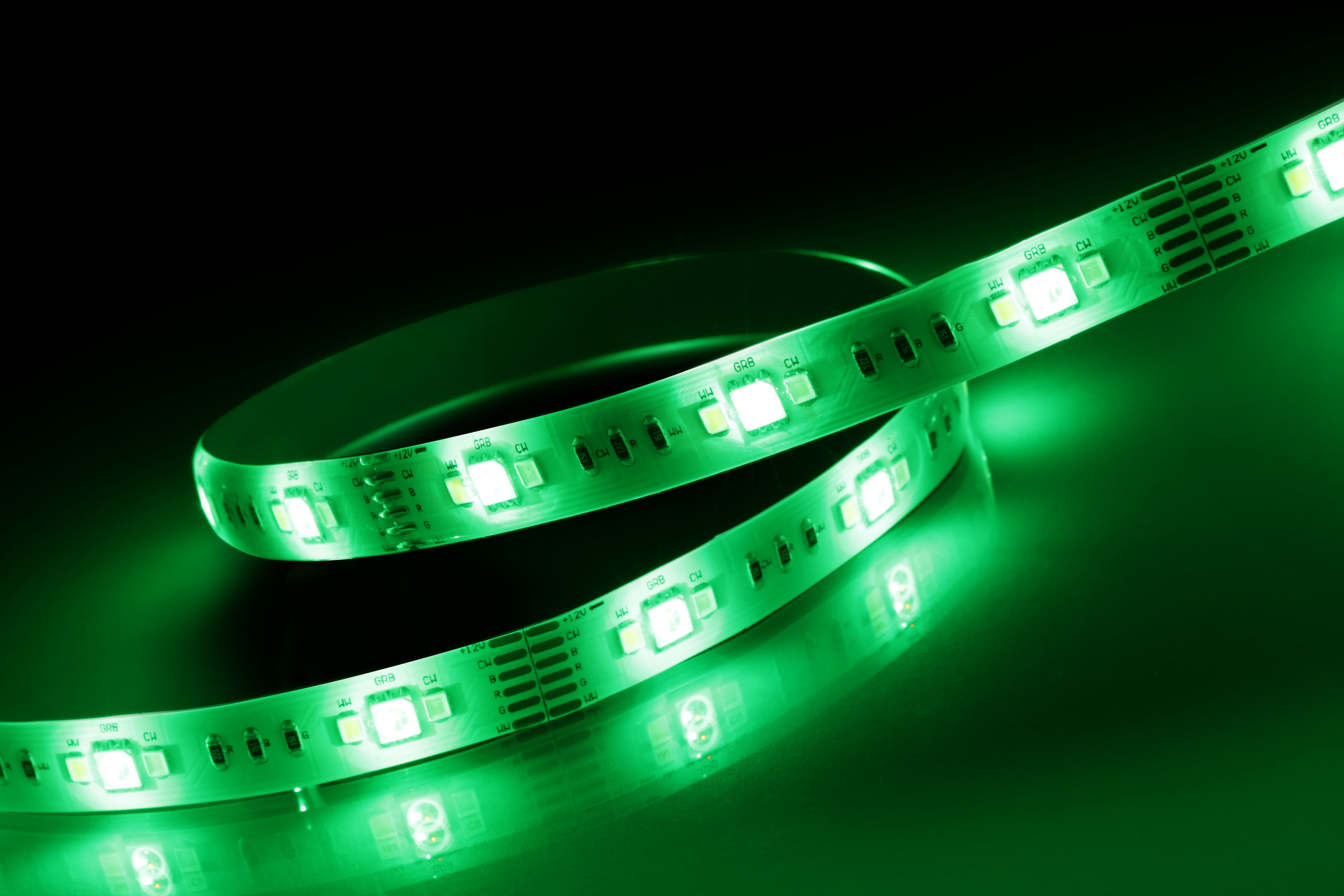 Grüne LED-Streifenlichter auf schwarzer Oberfläche. Die Lichter sind an und spiegeln sich auf der Oberfläche.