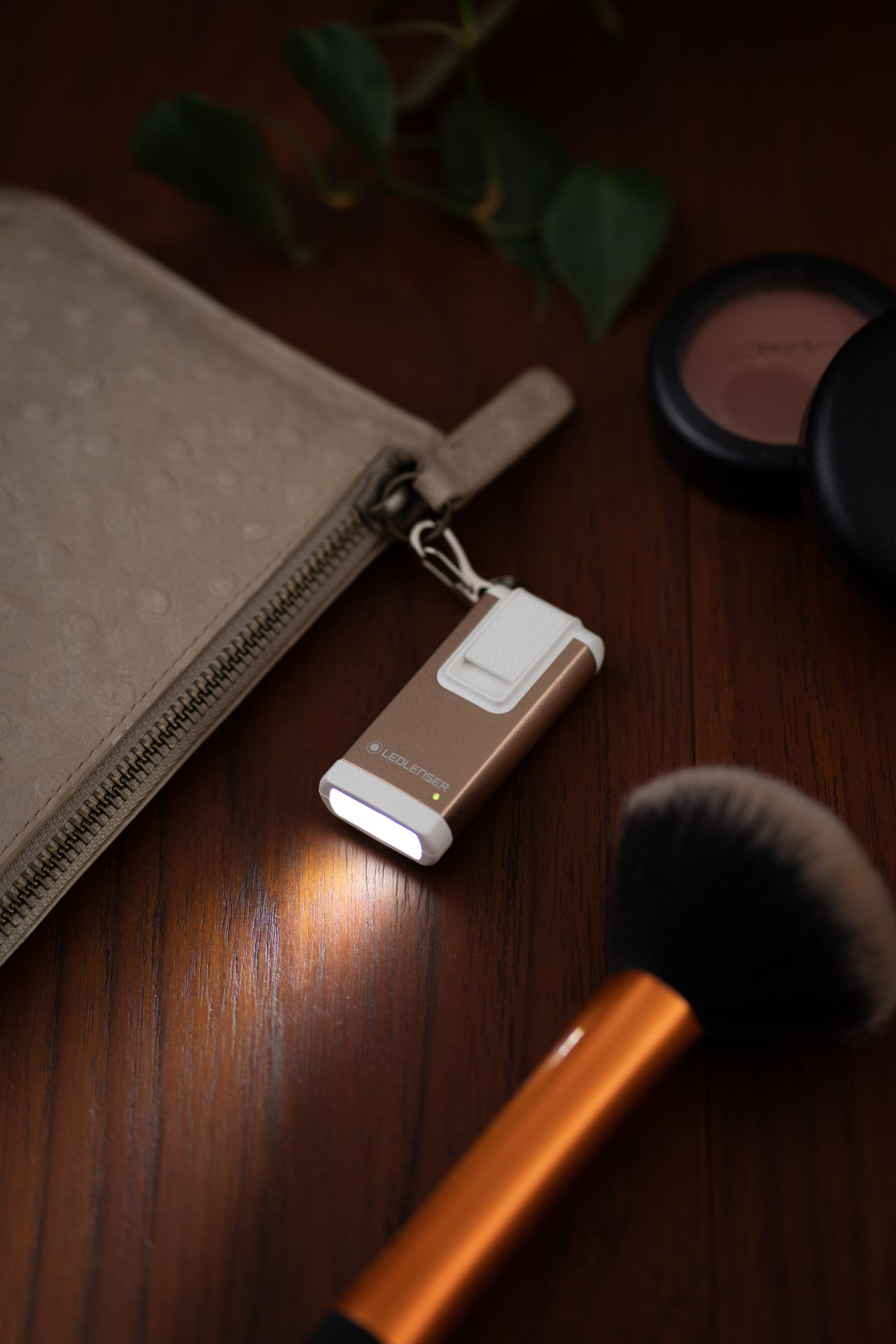 Une lampe de poche avec des pinceaux de maquillage et une trousse de maquillage sur bois.