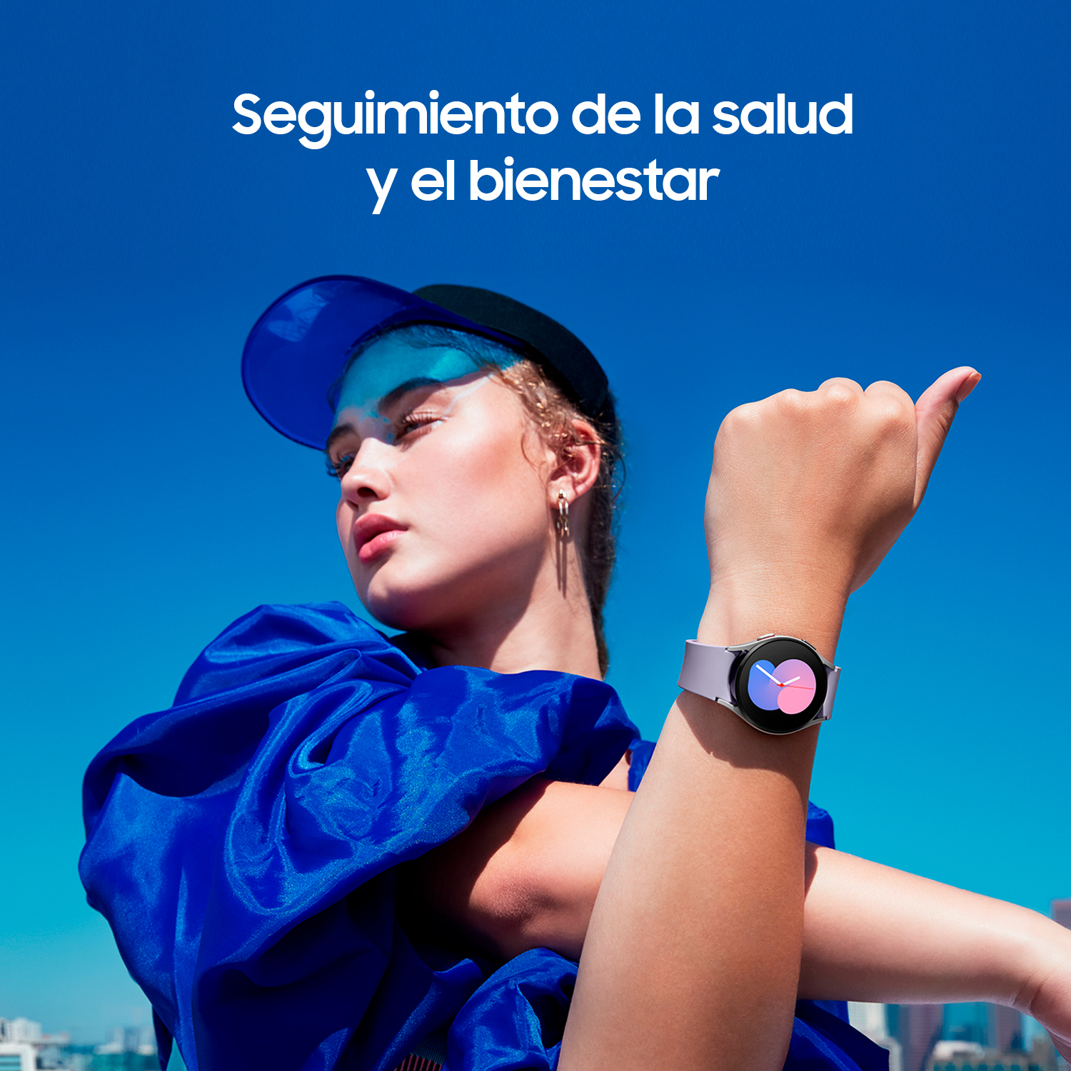 Una mujer con una parte superior azul y un reloj inteligente en la muñeca. Se estira frente a un telón de fondo.