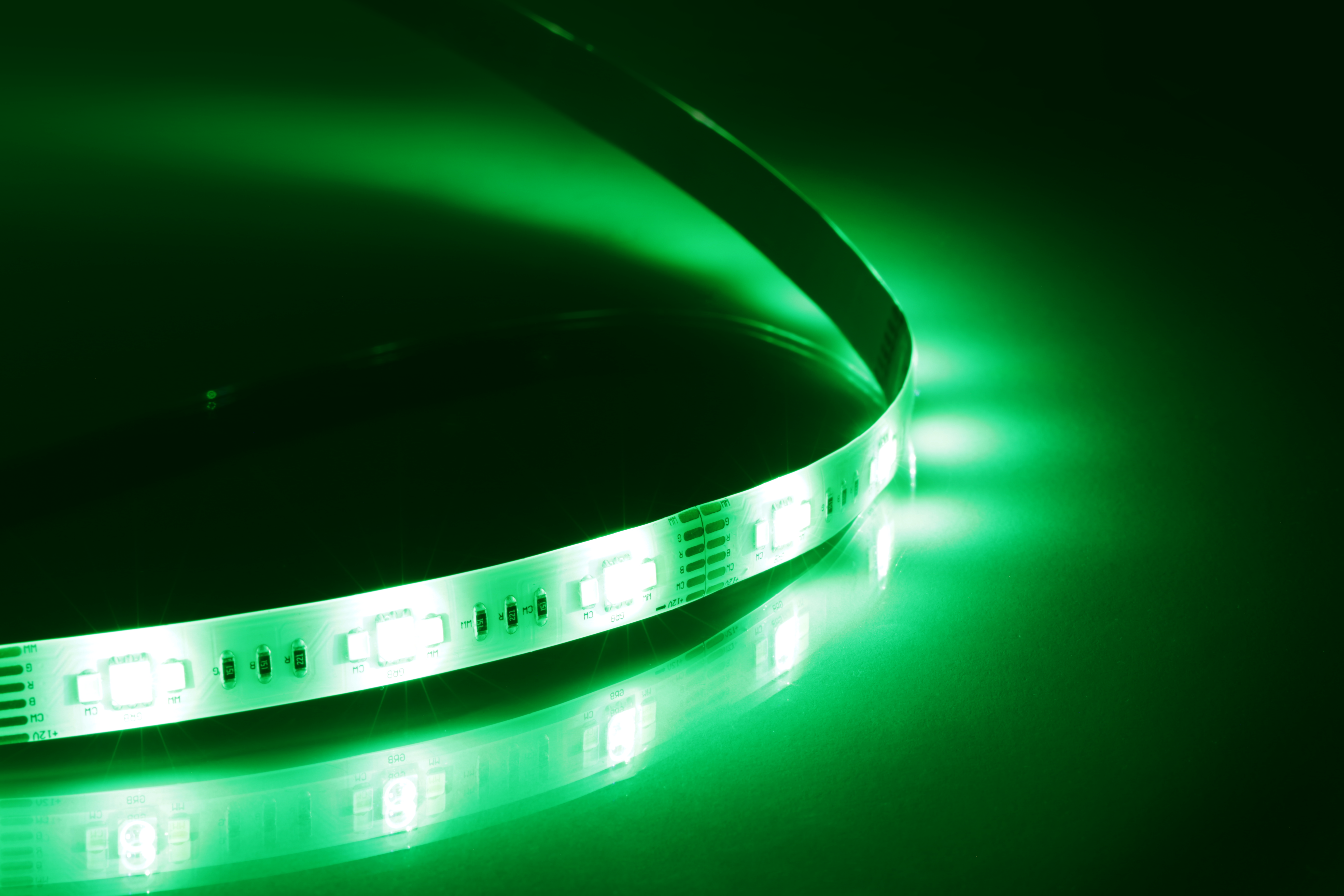 Ein grüner LED-Lichtstreifen ist auf einer reflektierenden Oberfläche aufgewickelt und leuchtet hell.
