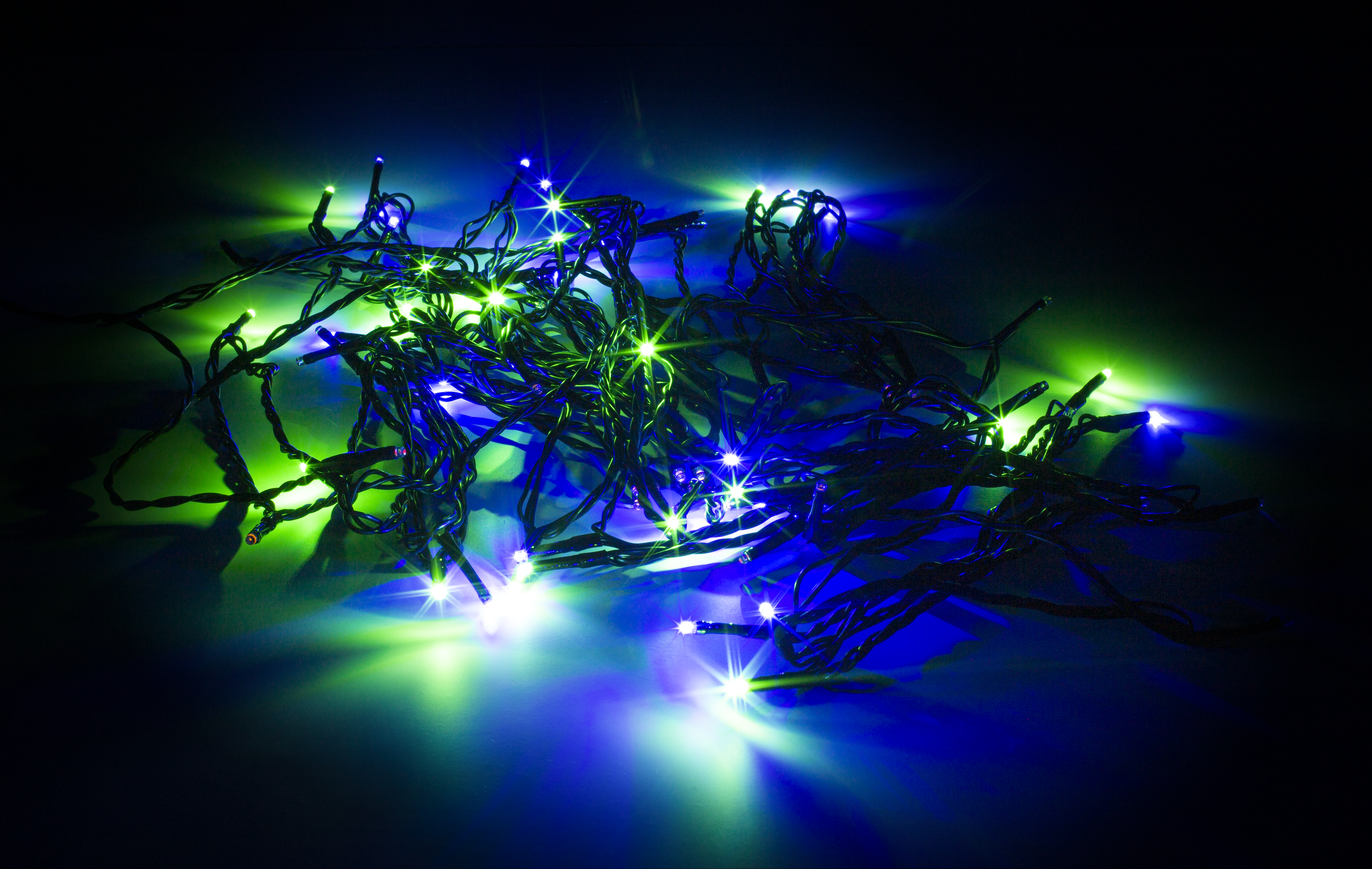 Ein Cluster aus grünen und blauen Lichterketten auf schwarzem Hintergrund. Die Lichter leuchten hell.