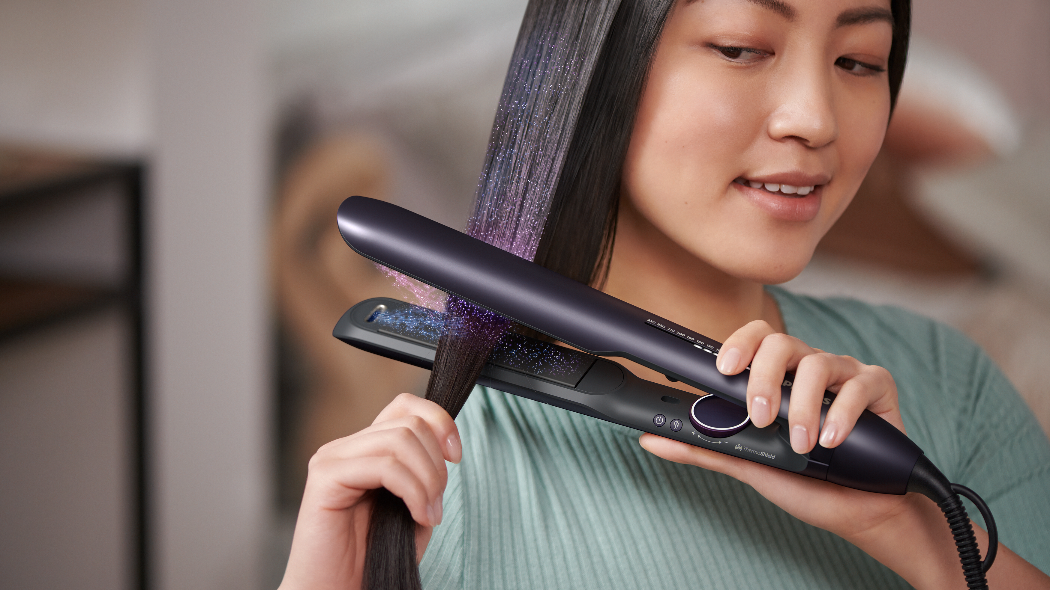 Una mujer usa una plancha para el cabello, mostrando un mechón con purpurina colorida.