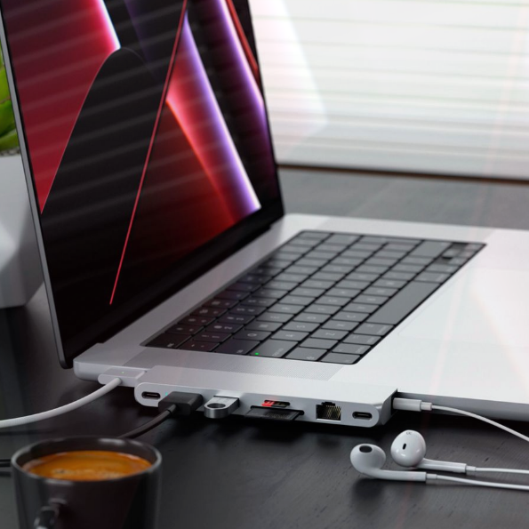 Ein Laptop mit angeschlossenem Hub, Kopfhörern und einer Kaffeetasse.