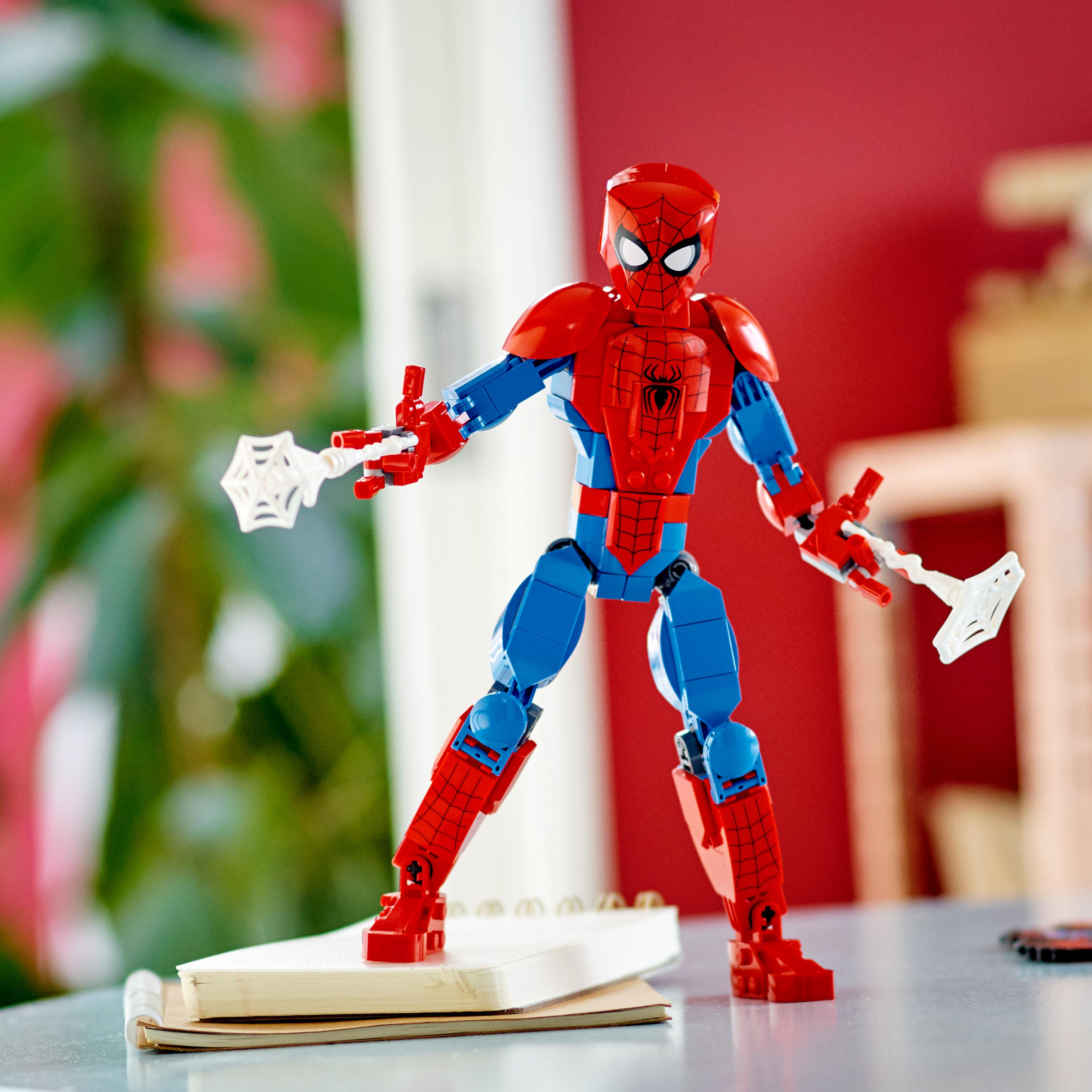 Spider-Man Actionfigur. Roter und blauer Anzug, weiße Web-Shooter. Steht auf einem Notizbuch.