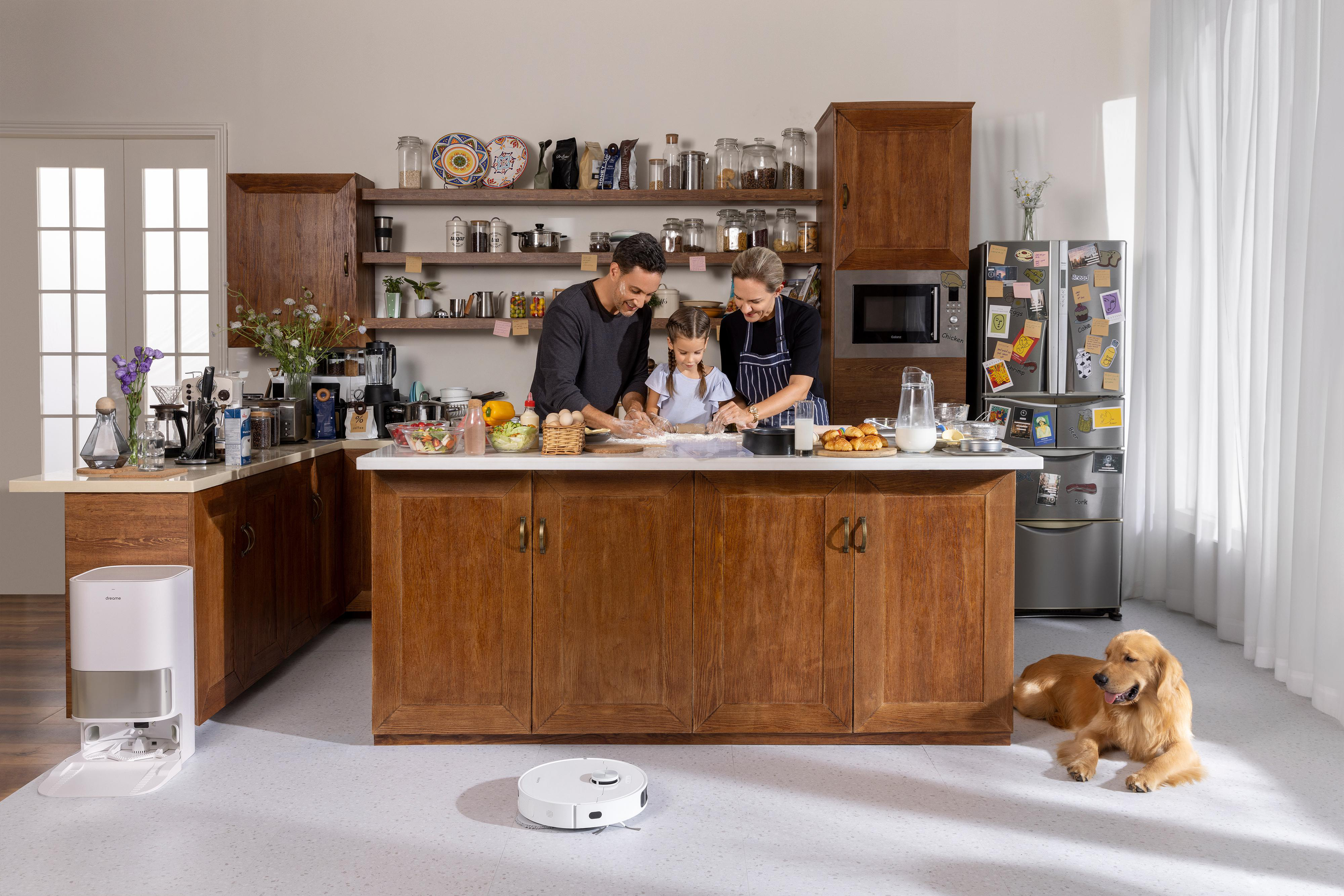 Familie kocht in Küche mit Roboterstaubsauger und Hund.
