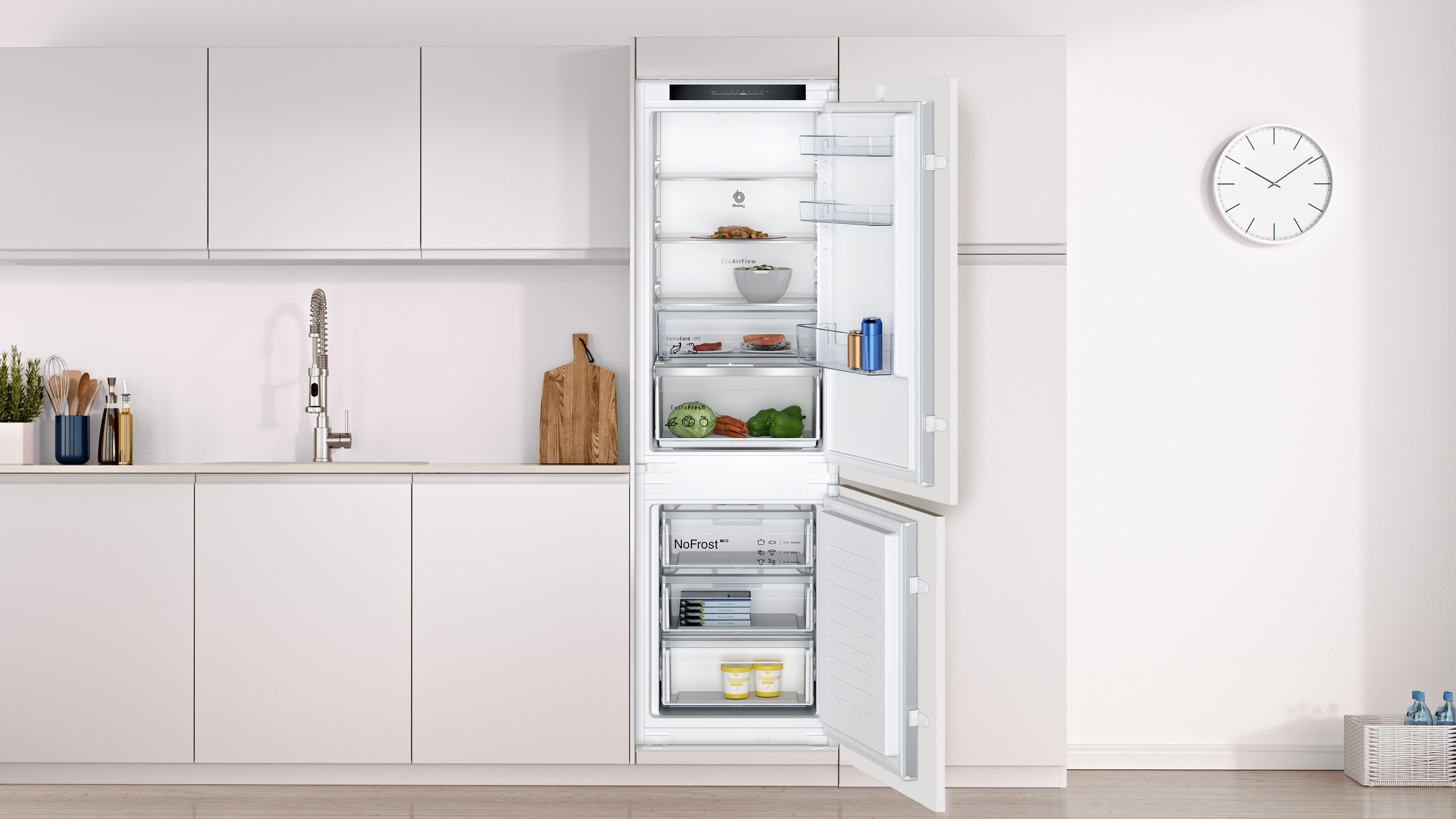 Cocina moderna con refrigerador abierto. Incluye tabla de cortar, reloj y fregadero. Refrigerador con comida y bebidas.