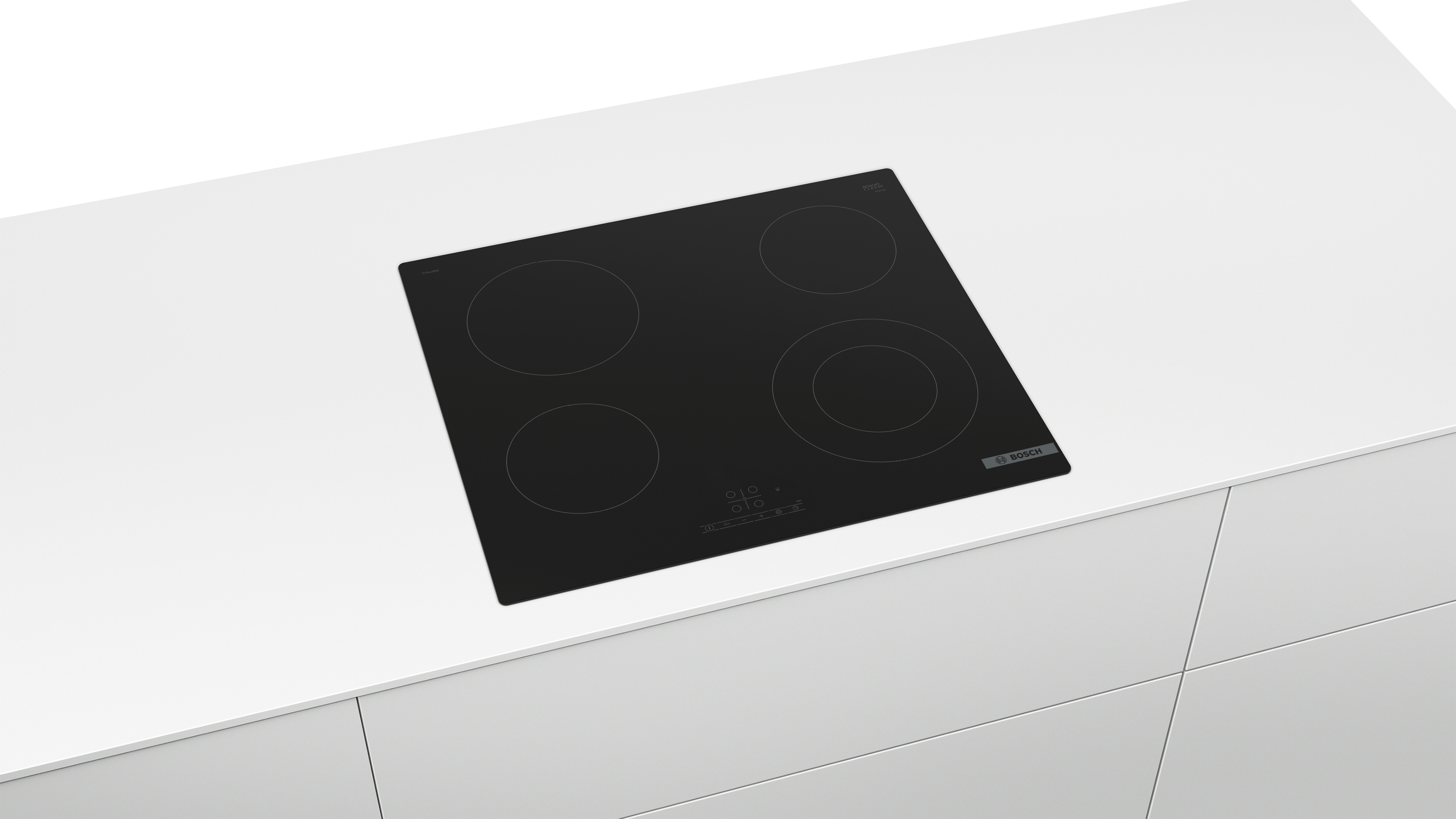 Placa de cocina eléctrica Bosch negra con cuatro quemadores sobre encimera blanca. Cajones de armario de cocina al fondo.