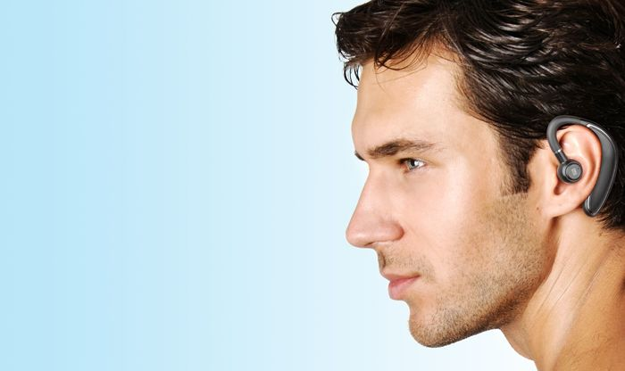 Un hombre con un auricular bluetooth. La cara del hombre mira hacia la izquierda. Fondo azul claro.