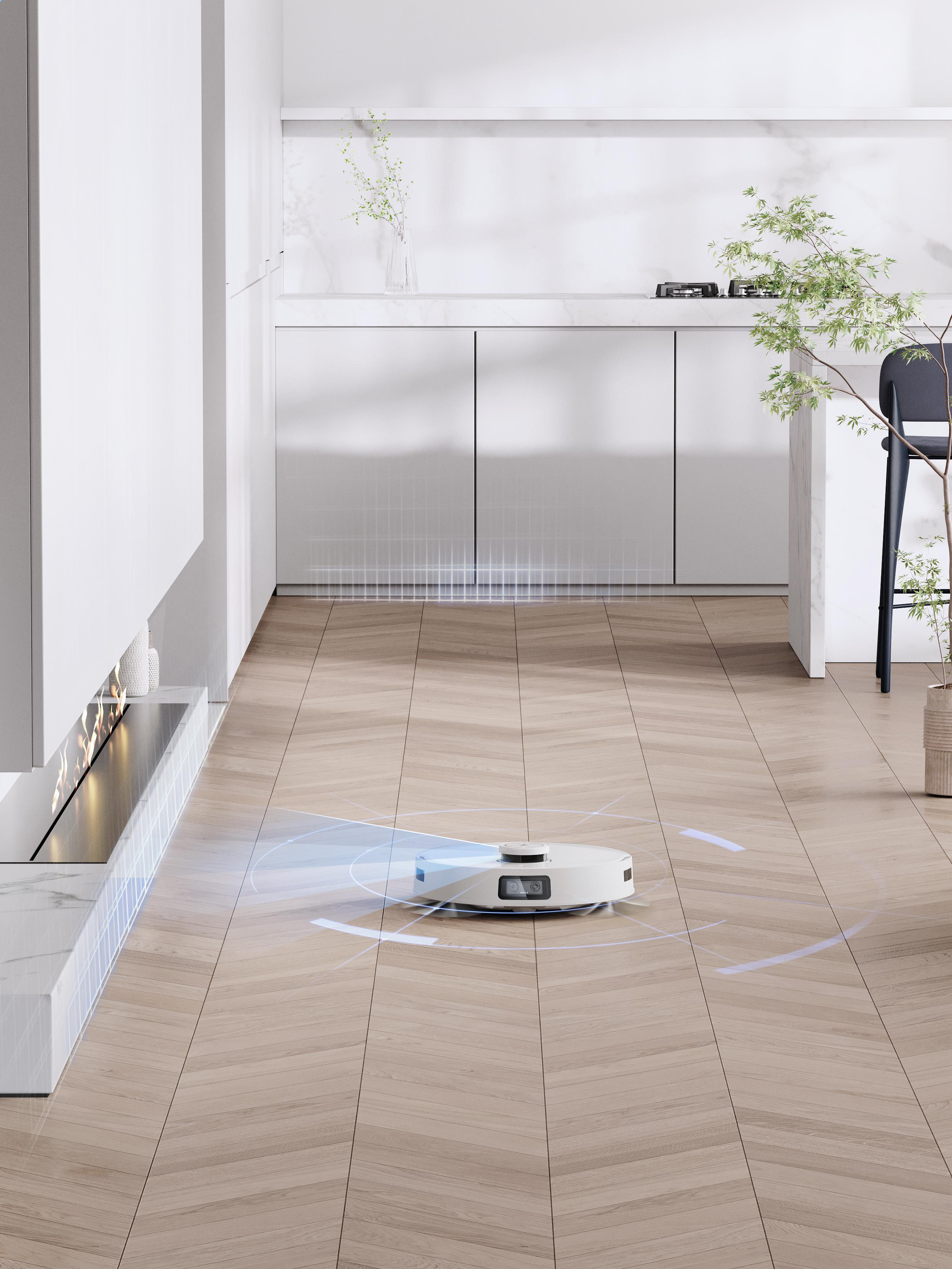 Ein weißer Roboter-Staubsauger reinigt einen Holzboden. Moderne Küche im Hintergrund.