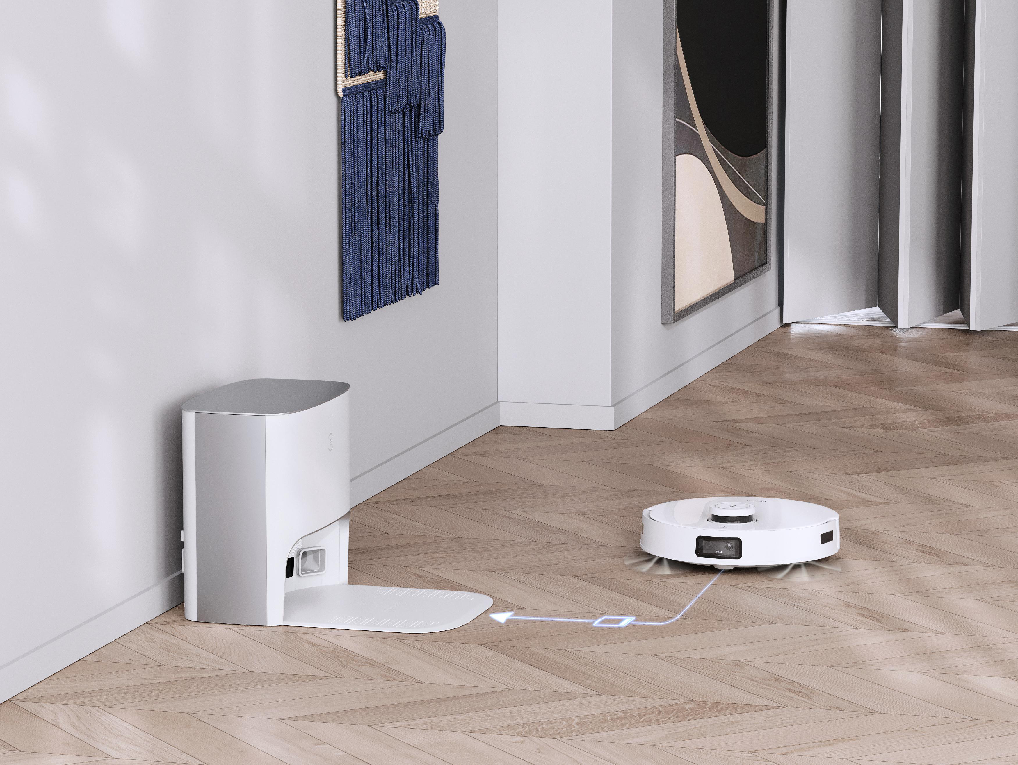 Ein Roboter-Staubsauger und eine Ladestation in einem Raum mit Holzböden und weißen Wänden.