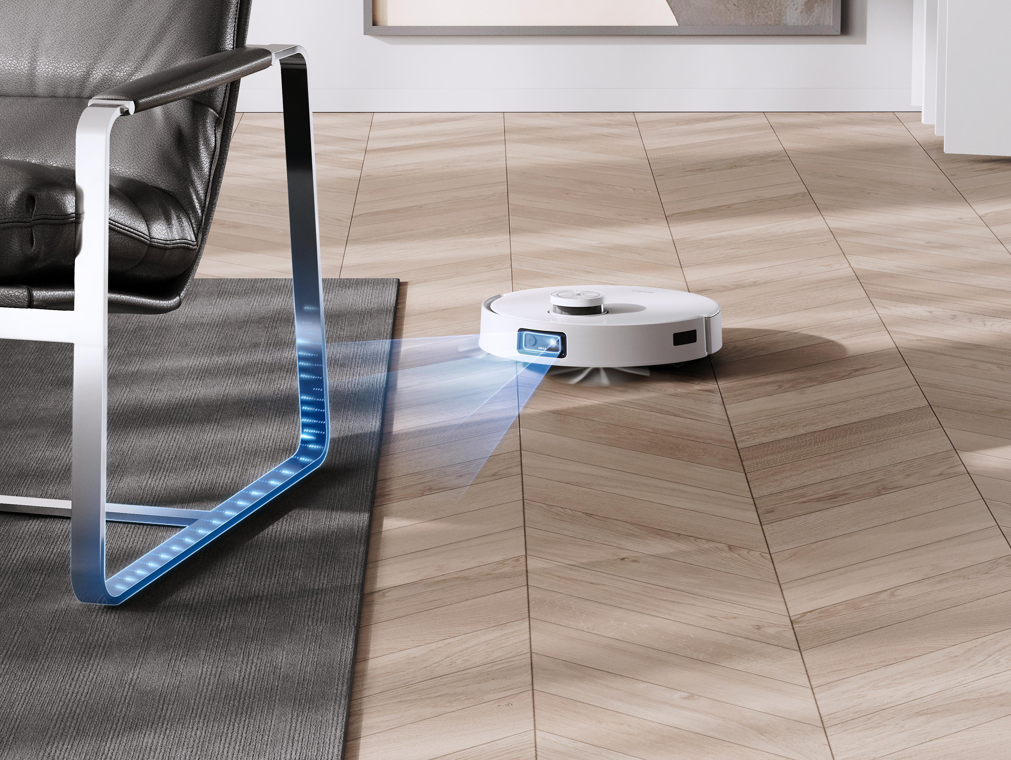 Ein Roboter-Staubsauger reinigt einen Holzboden neben einem Stuhl.