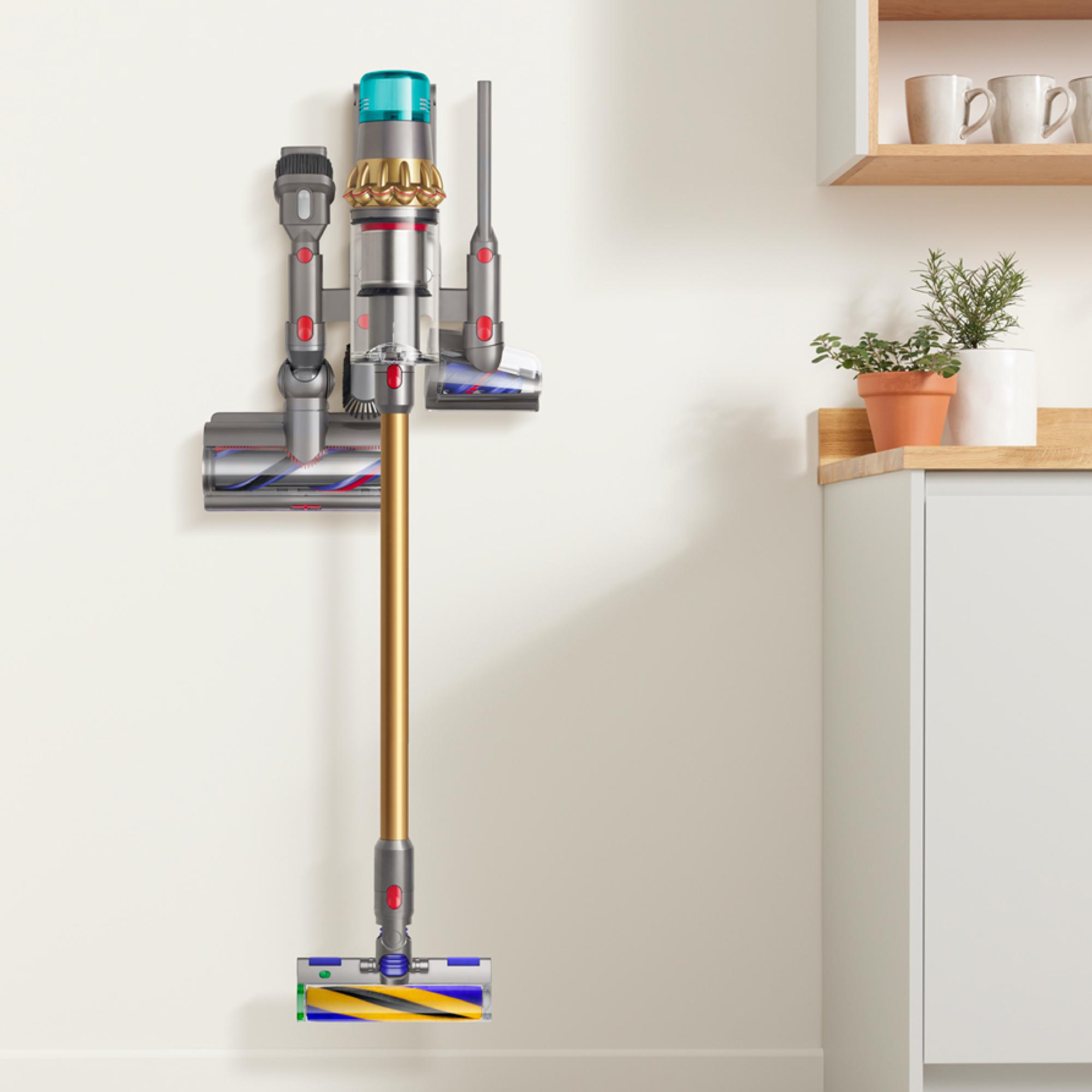 Dyson-Staubsauger an einer Wand in einem hellen Raum montiert. Verschiedene Aufsätze sind sichtbar.