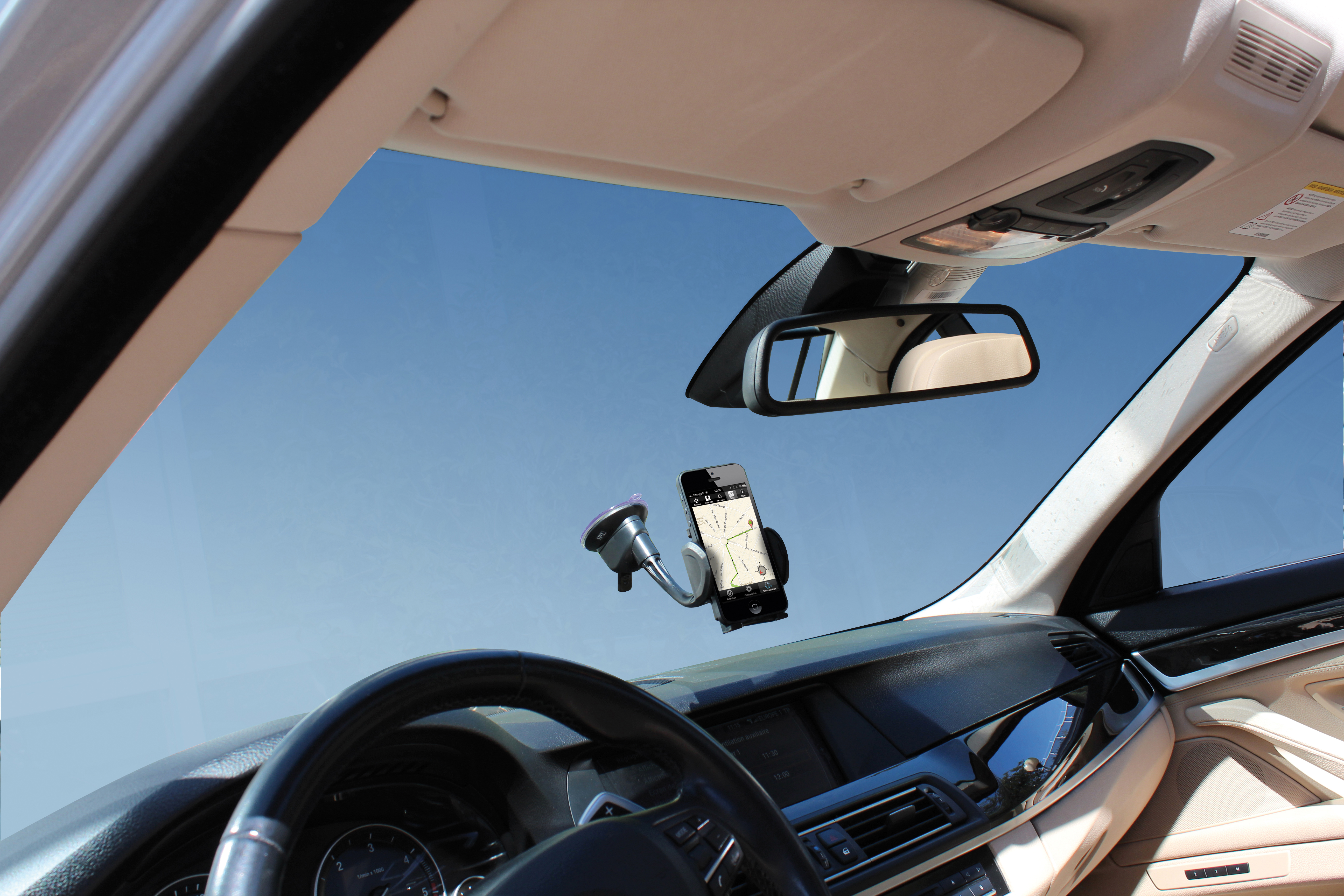 Intérieur de voiture avec un téléphone monté sur le pare-brise, affichant une application de navigation.