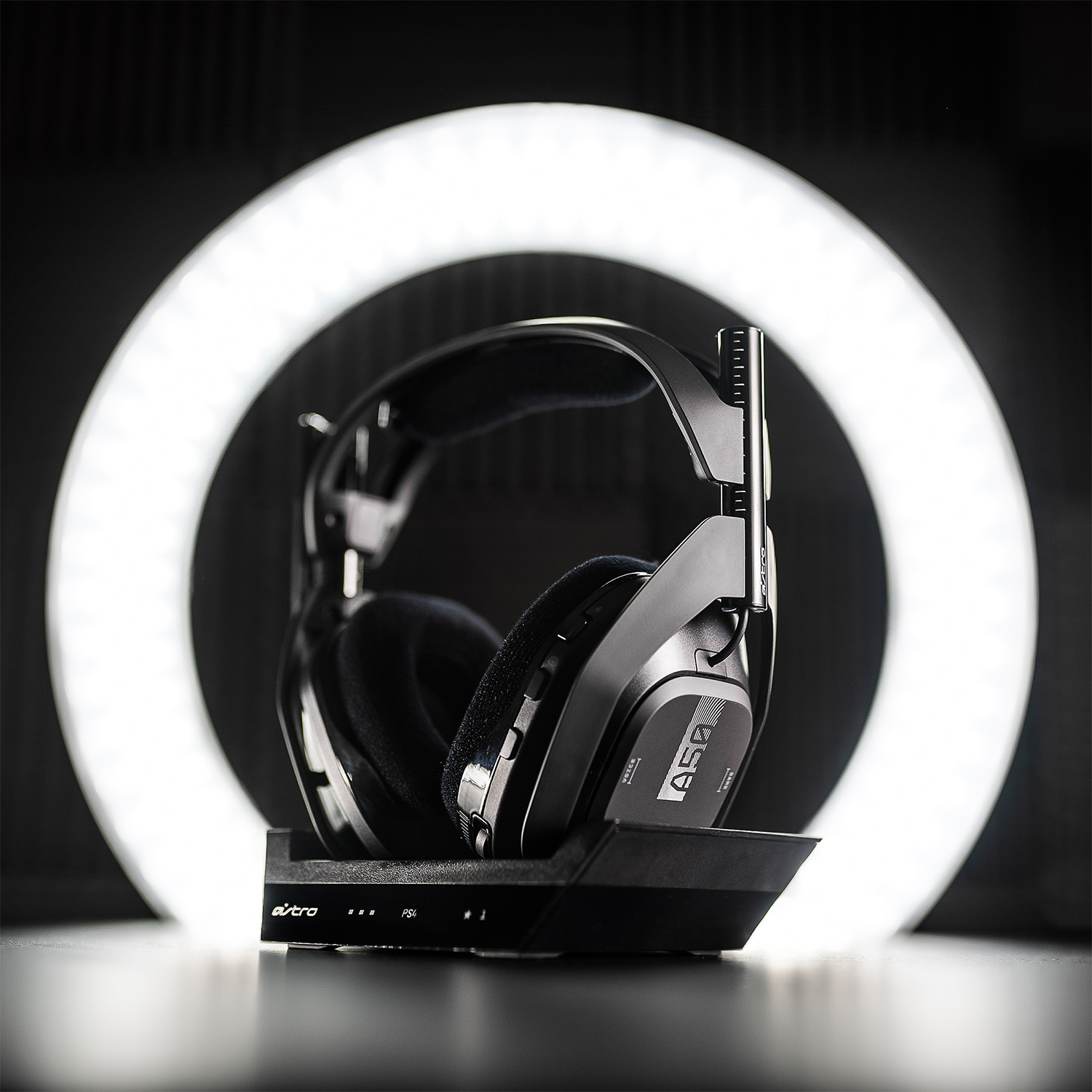 Casque de jeu Astro sur un support, devant une lumière annulaire brillante, avec un fond noir.