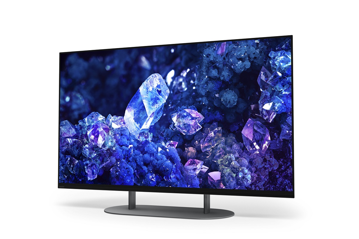 Büyük bir TV, beyaz bir arka plan üzerinde kristalleri görüntüler. TV'nin siyah bir çerçevesi ve bir standı var.