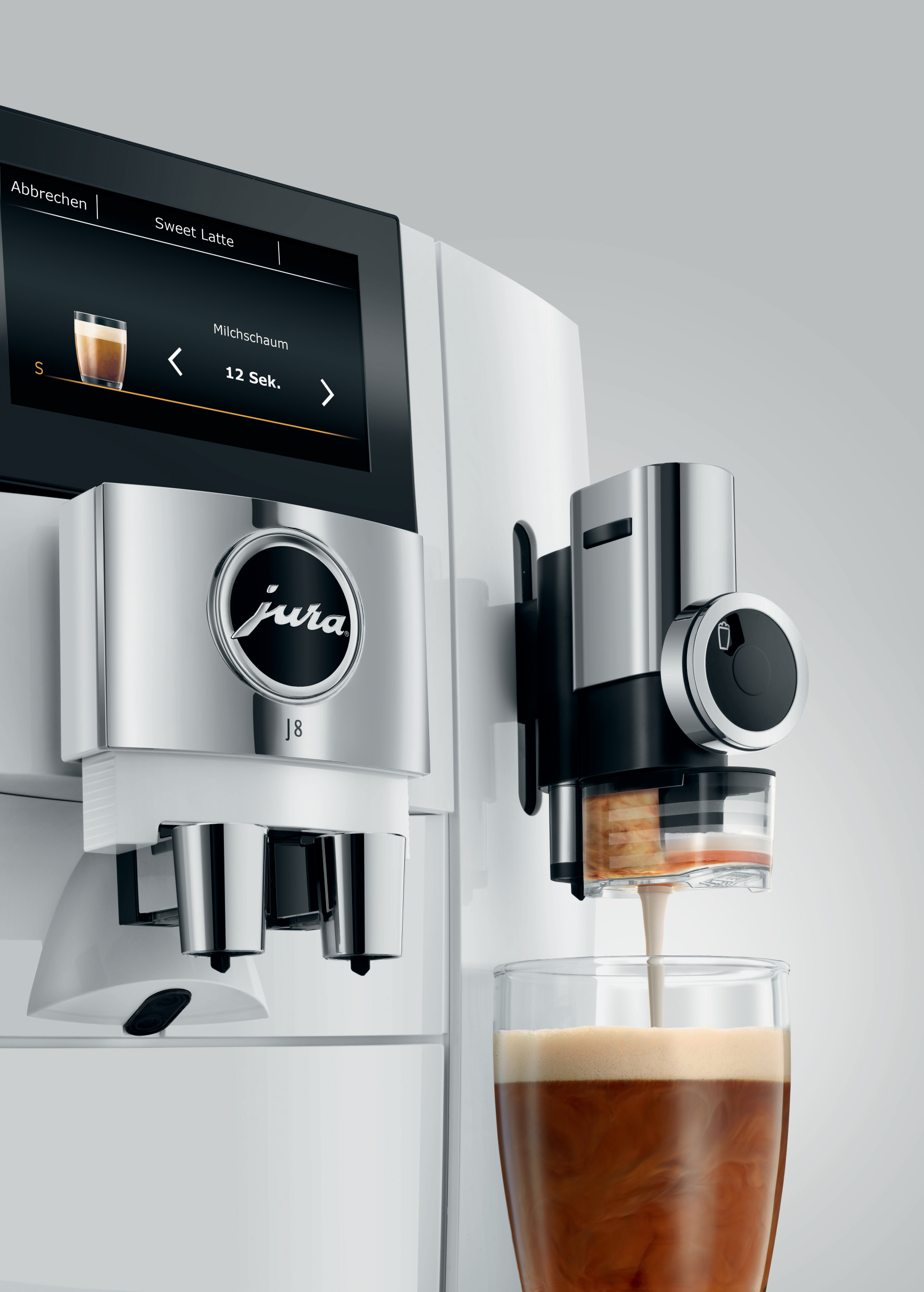 Eine Jura J8 Kaffeemaschine, die Kaffee in ein Glas mit Milch gießt.