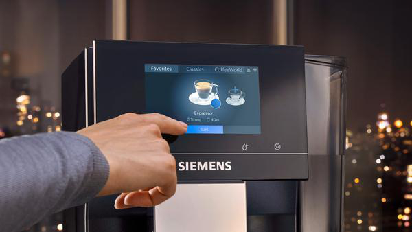 Eine Hand berührt einen Kaffeeautomaten-Bildschirm, der Optionen anzeigt.