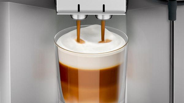 Kaffee wird in ein Glas gegossen, wodurch Schichten aus Kaffee und Schaum entstehen.