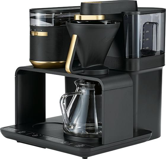 Schwarze und goldene Kaffeemaschine mit klarer Karaffe und Wassertank, auf schwarzer Basis.