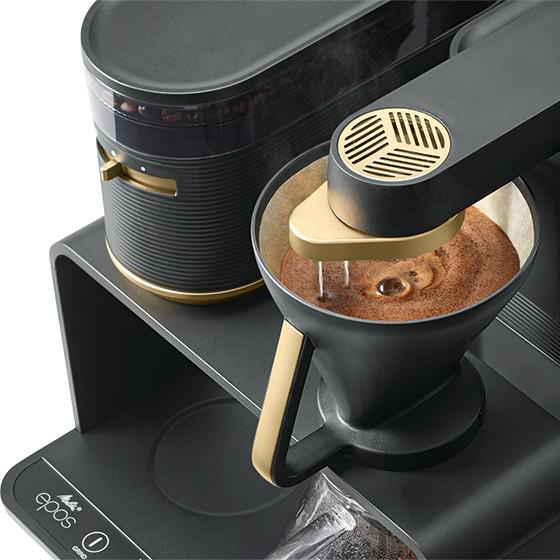 Kaffeemaschine mit Filter, Kaffee gießt, und eine Mühle, die den Brühvorgang zeigt.