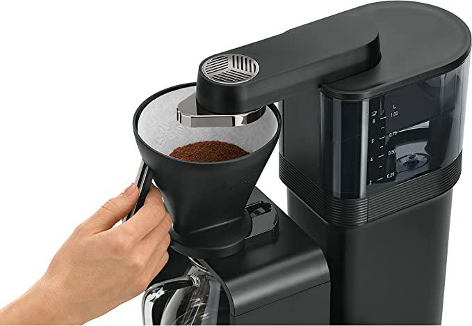 Kaffeemaschine mit einer Hand, die Kaffeepulver hinzufügt.