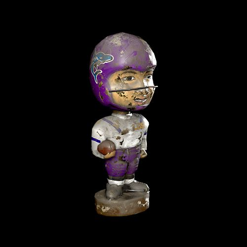 Un bobblehead usé d'un joueur de football américain avec un casque et un uniforme violets, sur fond noir.