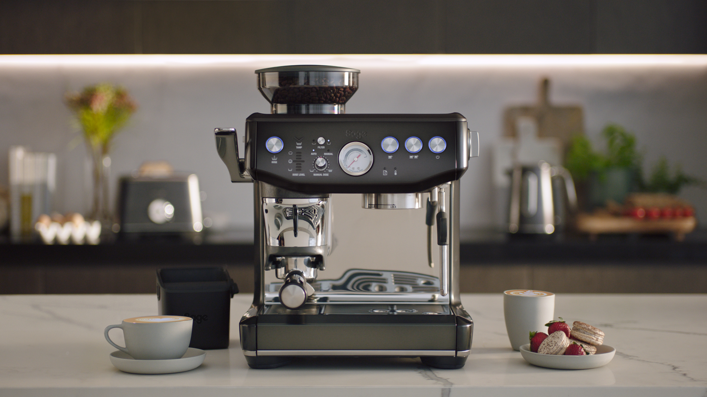 Schwarze Espressomaschine mit Zubehör auf einer weißen Arbeitsplatte.