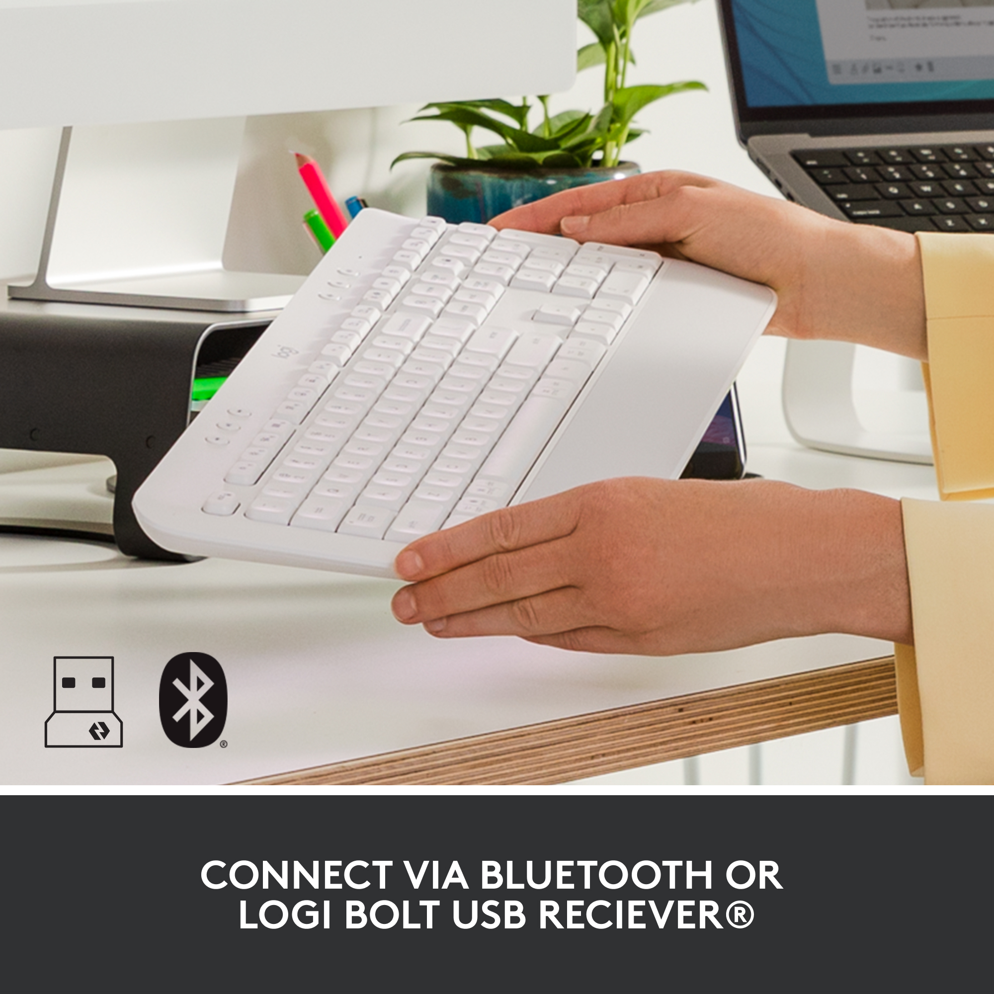 Hände tippen auf einer weißen Tastatur. Symbole für Bluetooth und USB-Empfänger.