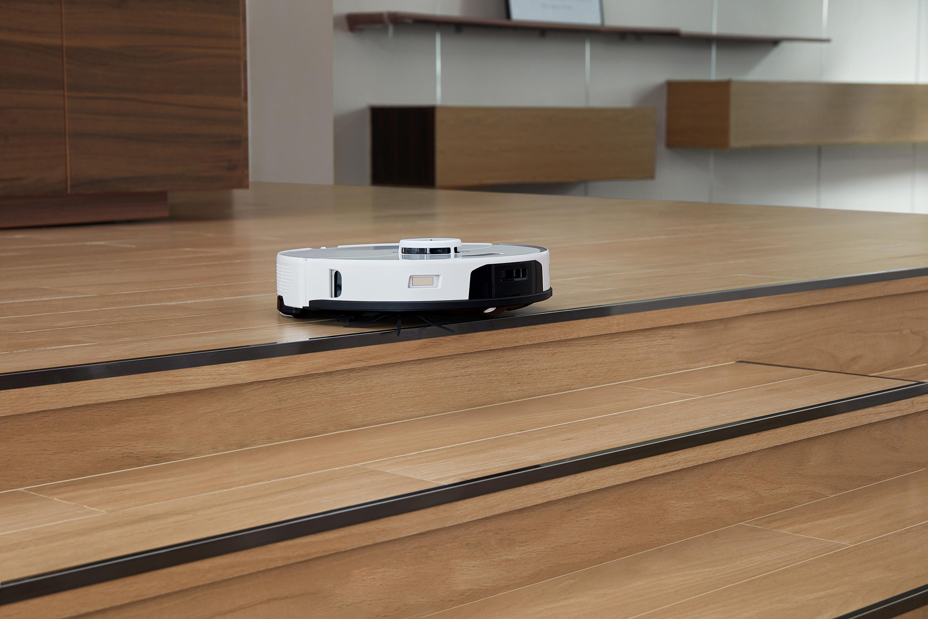 Roboter-Staubsauger auf einem Holzboden. Der Boden hat eine Stufe nach unten.
