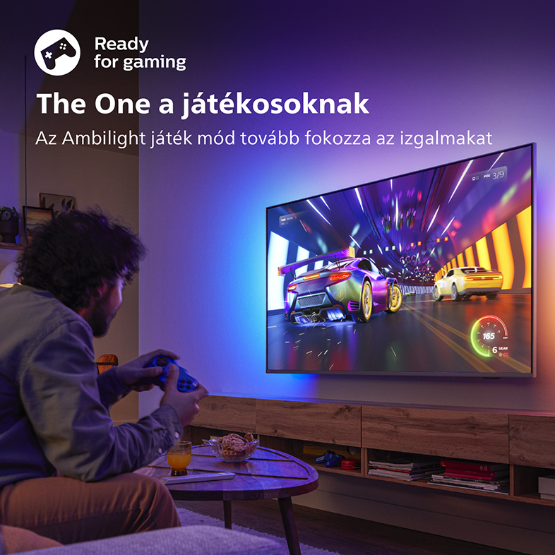 Egy férfi videójátékozik, a TV egy versenyszámot mutat. A TV-nek színes lámpái vannak.