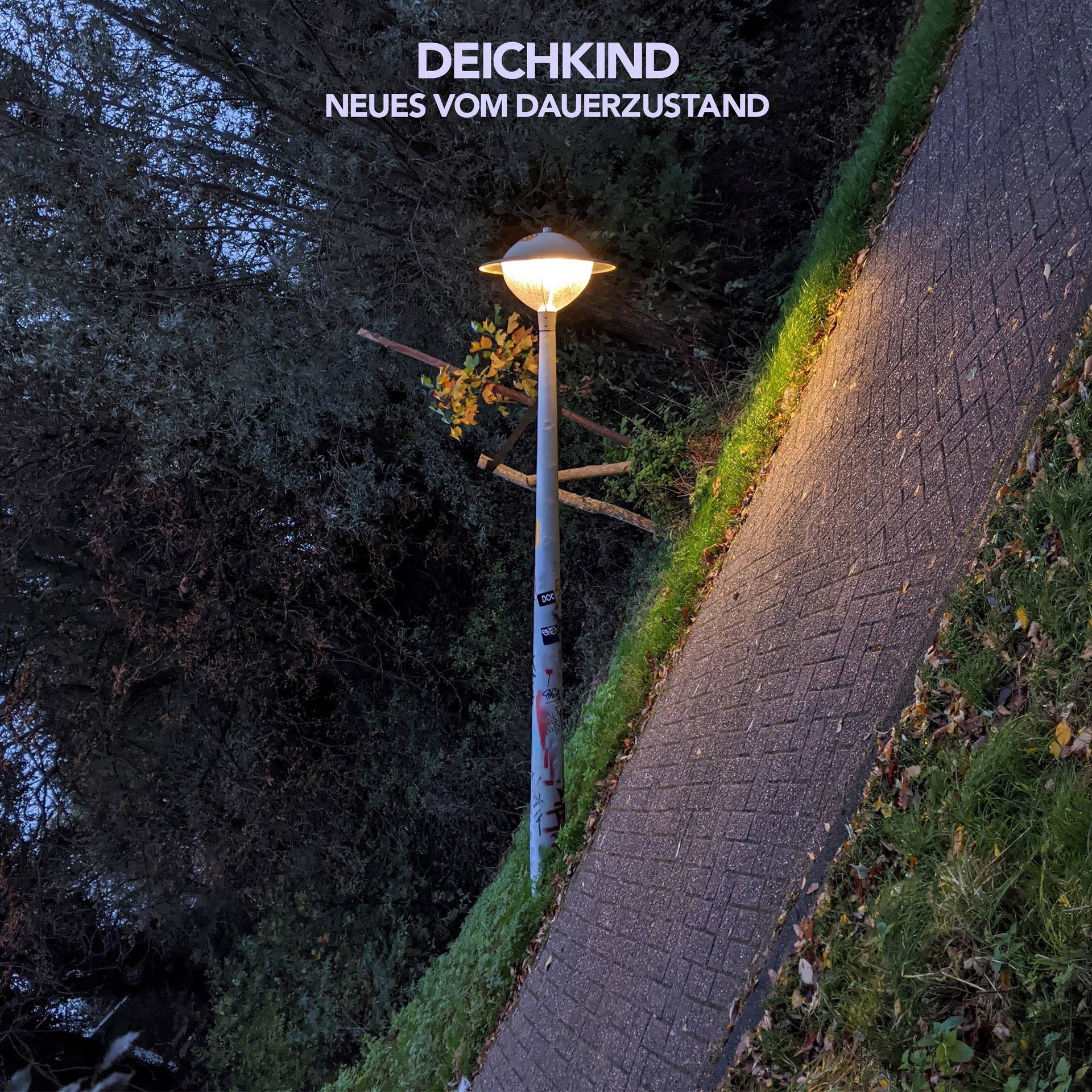 Eine Straßenlaterne beleuchtet einen Weg. Text 'DEICHKIND' oben.