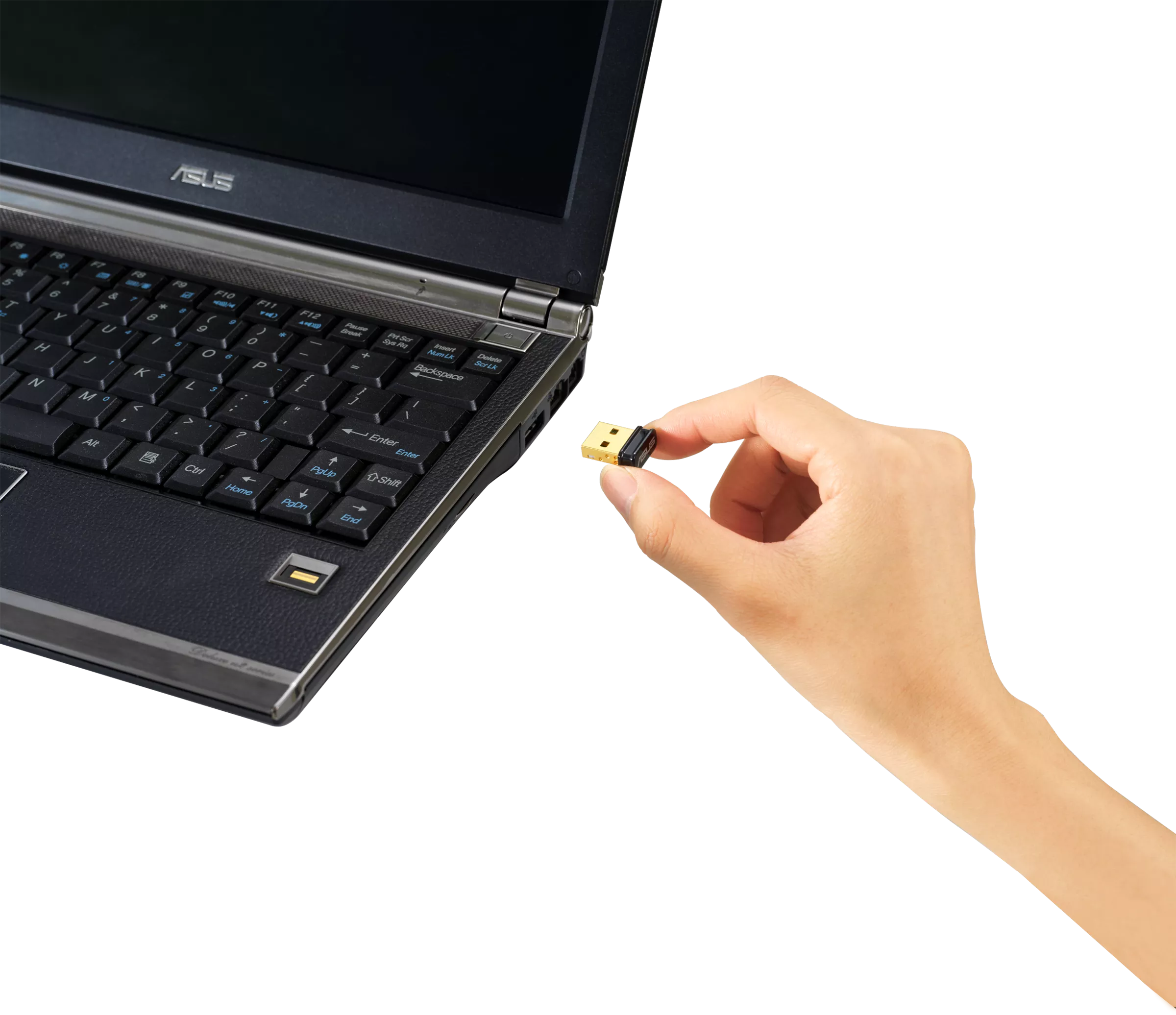 Eine Hand hält einen kleinen schwarzen USB-Stick in der Nähe eines Laptops.