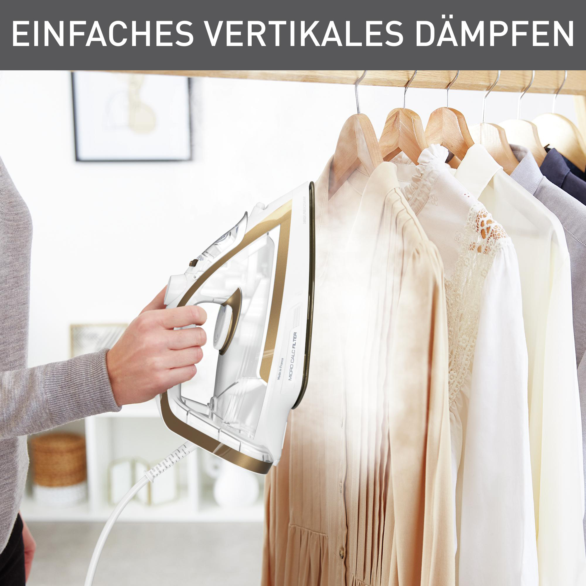 Eine Frau bügelt Kleidung auf einem Bügel. Das Bügeleisen ist weiß und gold.