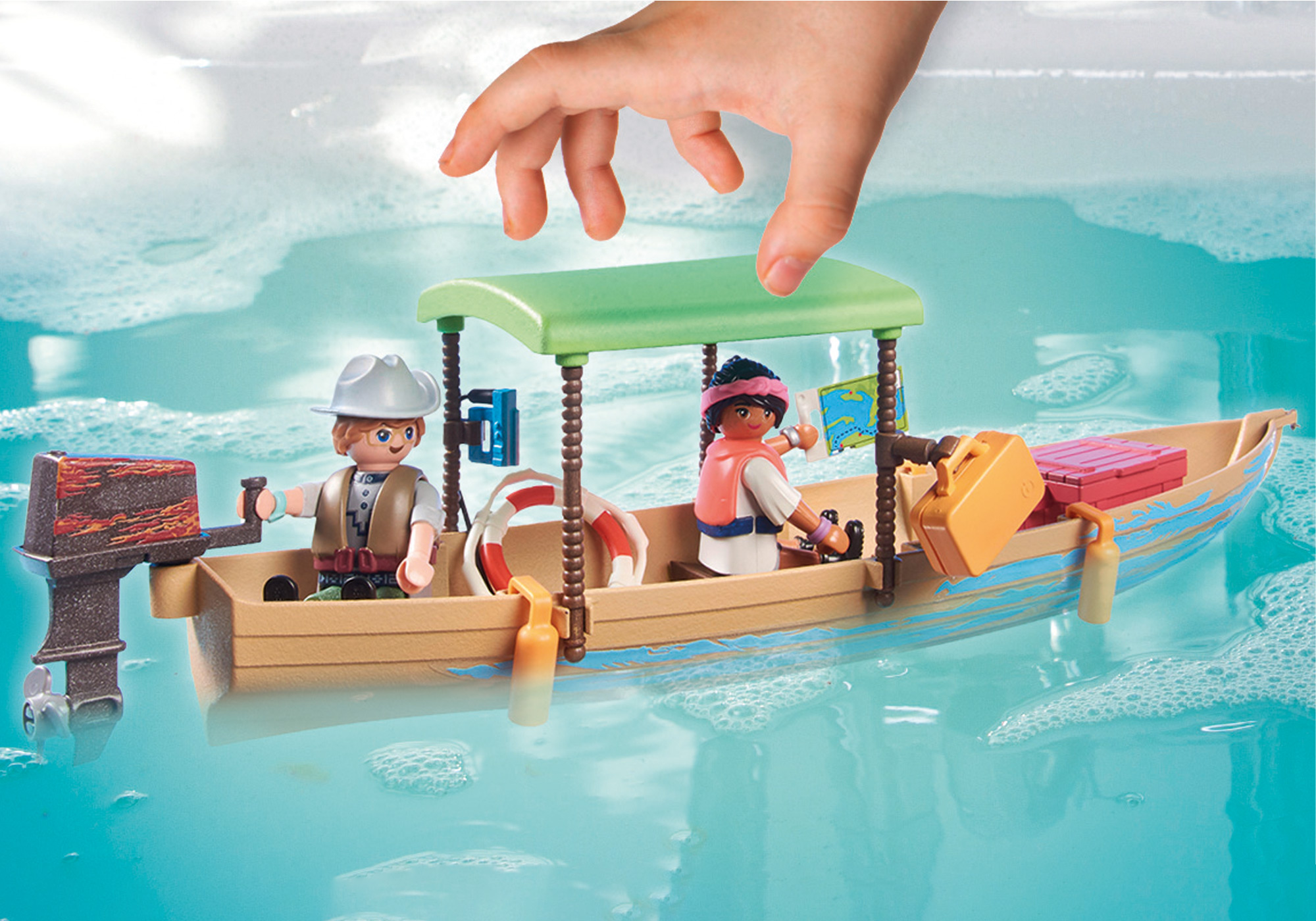 Spielzeugboot im Wasser, mit zwei Figuren und einer Hand. Grünes Verdeck, blaues Wasser.
