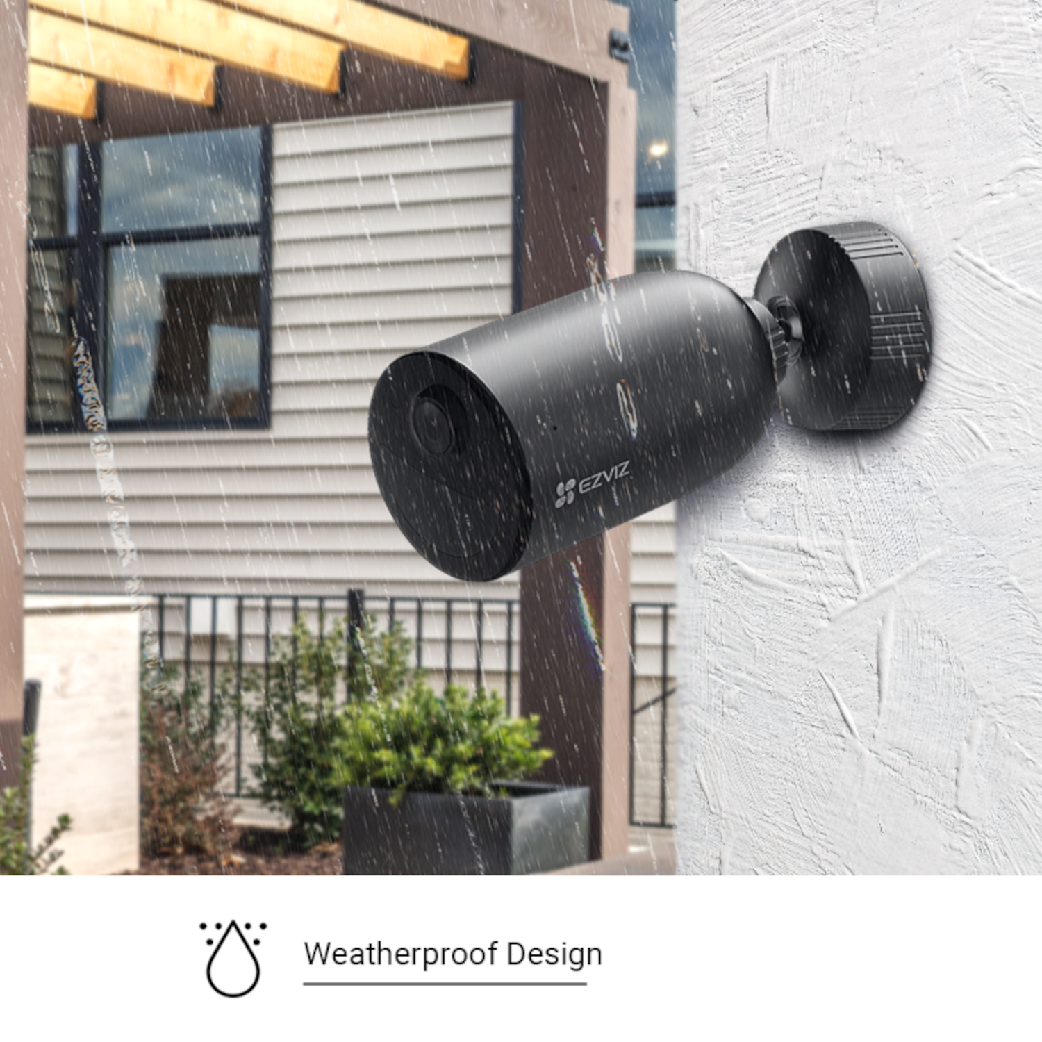 Black security camera mounted on white wall. Raindrops are visible. The camera is outdoors.