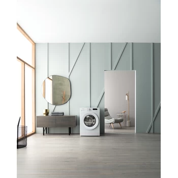 Een moderne, lichte badkamer heeft een wasmachine, spiegel en open deuropening.