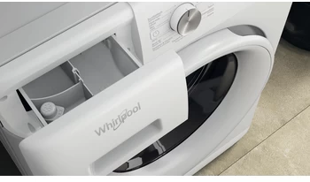 Witte Whirlpool wasmachine, wasmiddellade open, met vakken en fles, close-up.