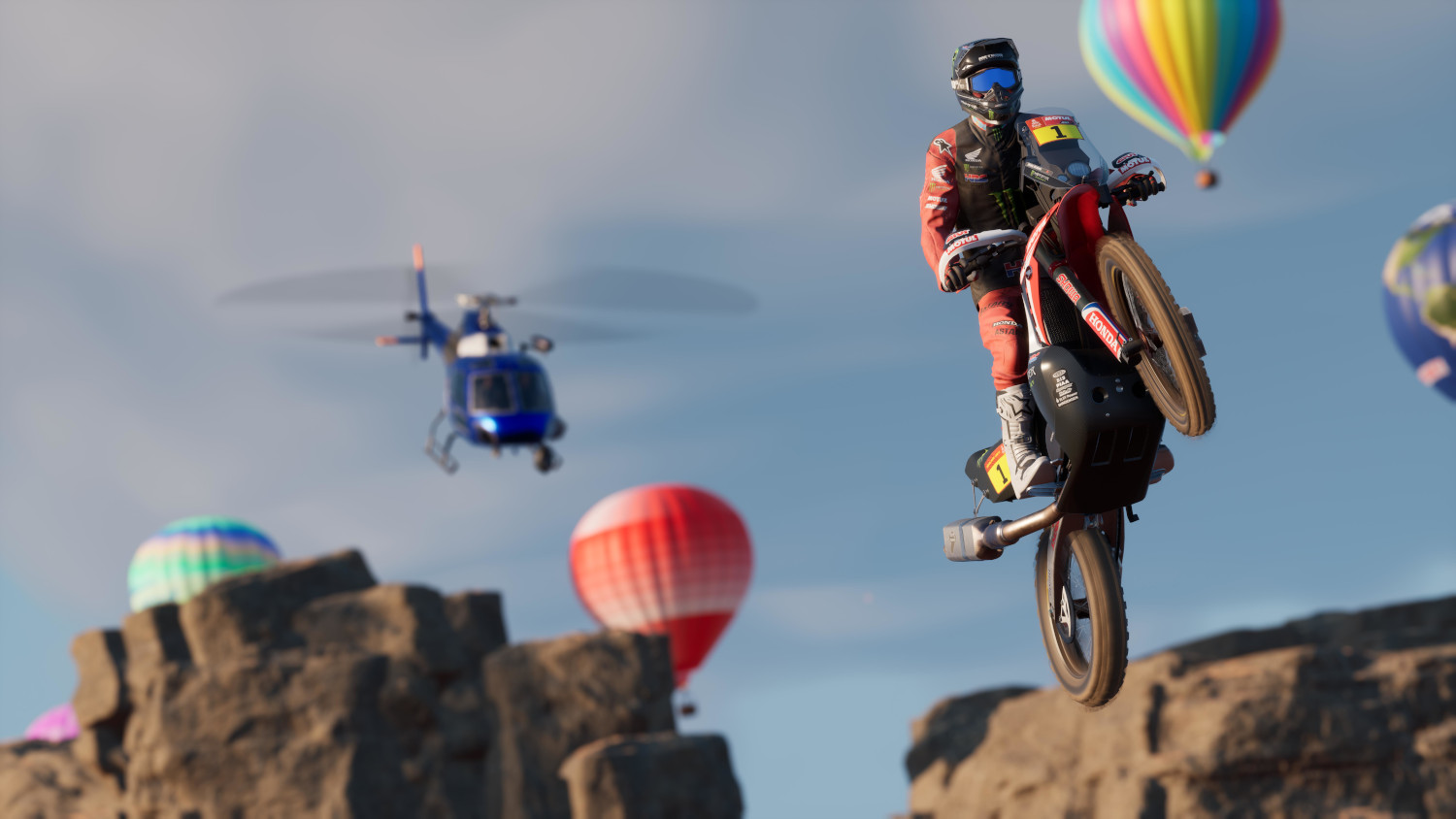 Een motorcrosser die een wheelie doet met luchtballonnen in de lucht.