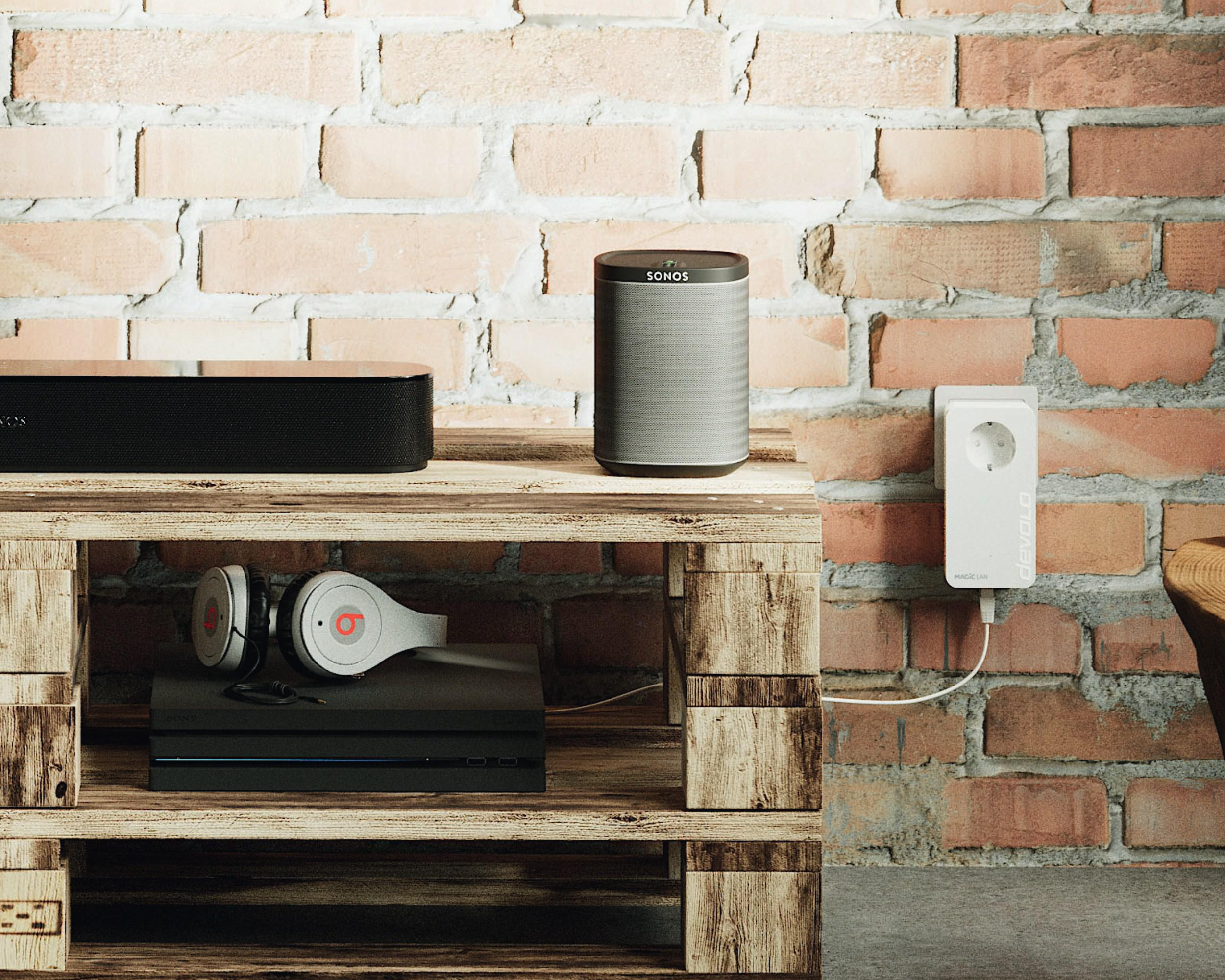 Entertainment-Setup mit Sonos Soundbar und Lautsprecher auf einem Holzregal vor einer Ziegelmauer.