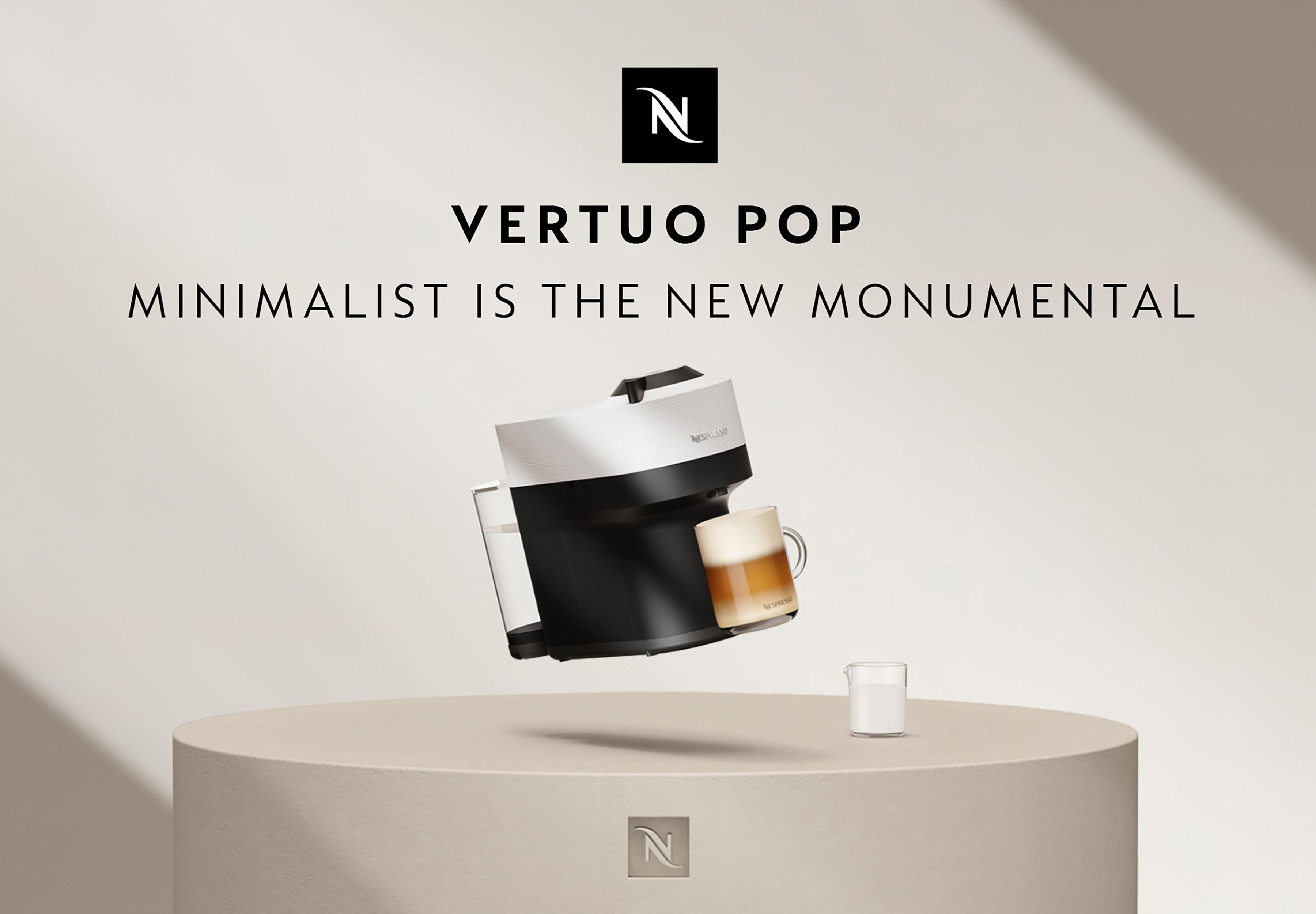 Nespresso Vertuo Pop-Maschine mit Tasse und Milchkännchen auf einer Plattform. Text: Minimalistisch ist das neue Monumentale.