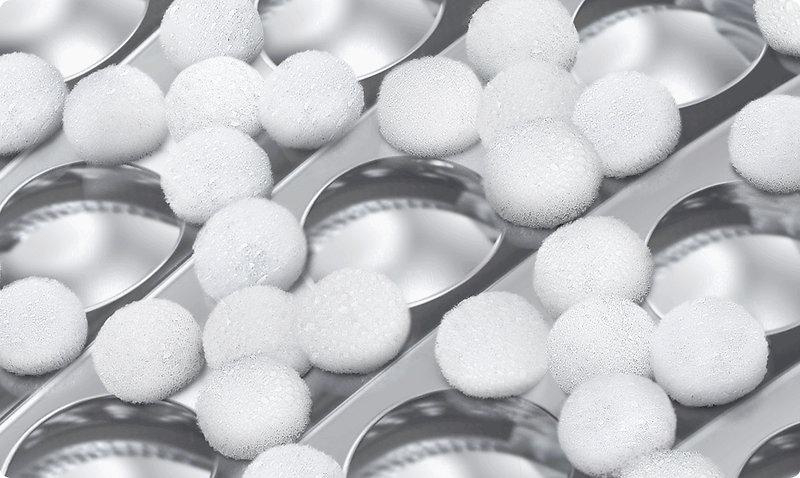 Nahaufnahme eines Metallreibe mit vielen kleinen weißen Kugeln auf der Oberfläche. Die Kugeln sind gleichmäßig verteilt.