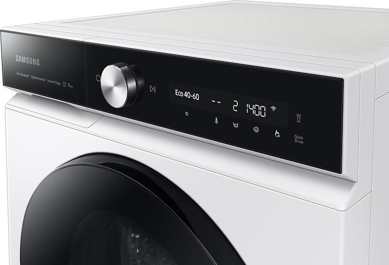 Eine weiße Samsung-Waschmaschine ist abgebildet. Sie hat ein schwarzes Bedienfeld mit einem Drehknopf, Display und verschiedenen Symbolen.
