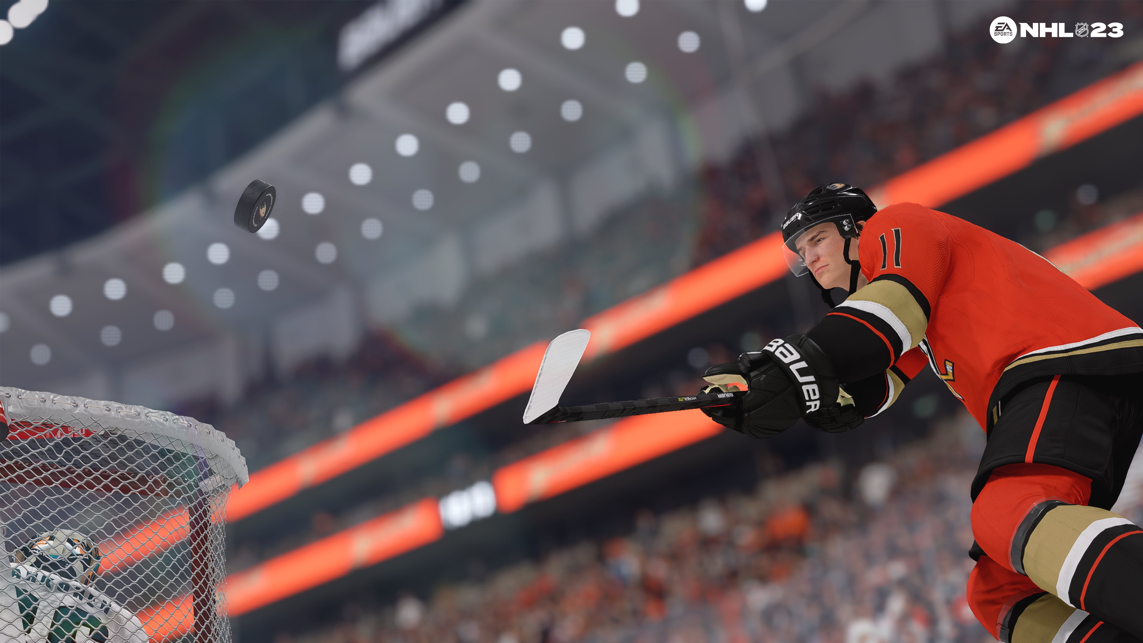 Ein Hockeyspieler im orangefarbenen Trikot schießt den Puck in Richtung Tor.