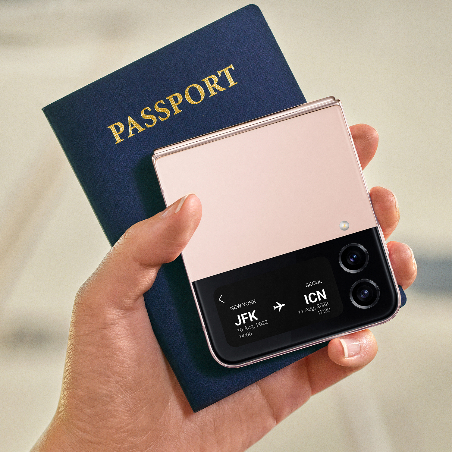 Mano sosteniendo un teléfono plegable rosa junto a un pasaporte.