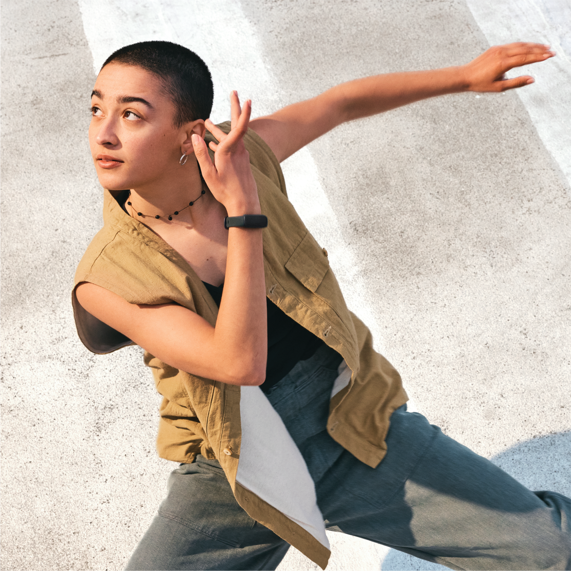Une jeune femme en gilet et pantalon, faisant une pose de danse sur une surface blanche.
