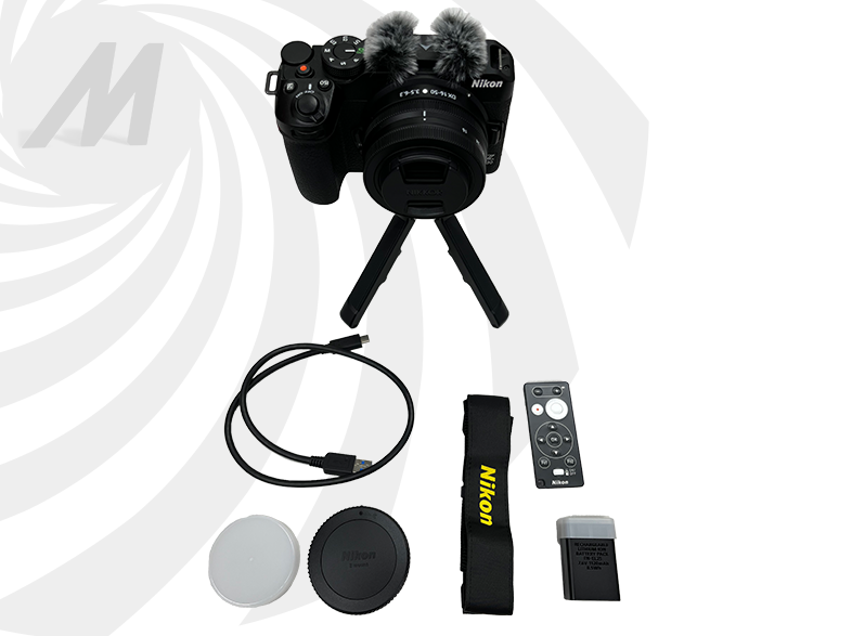 Kit caméra avec appareil photo, trépied, microphone, câbles et accessoires sur fond blanc.