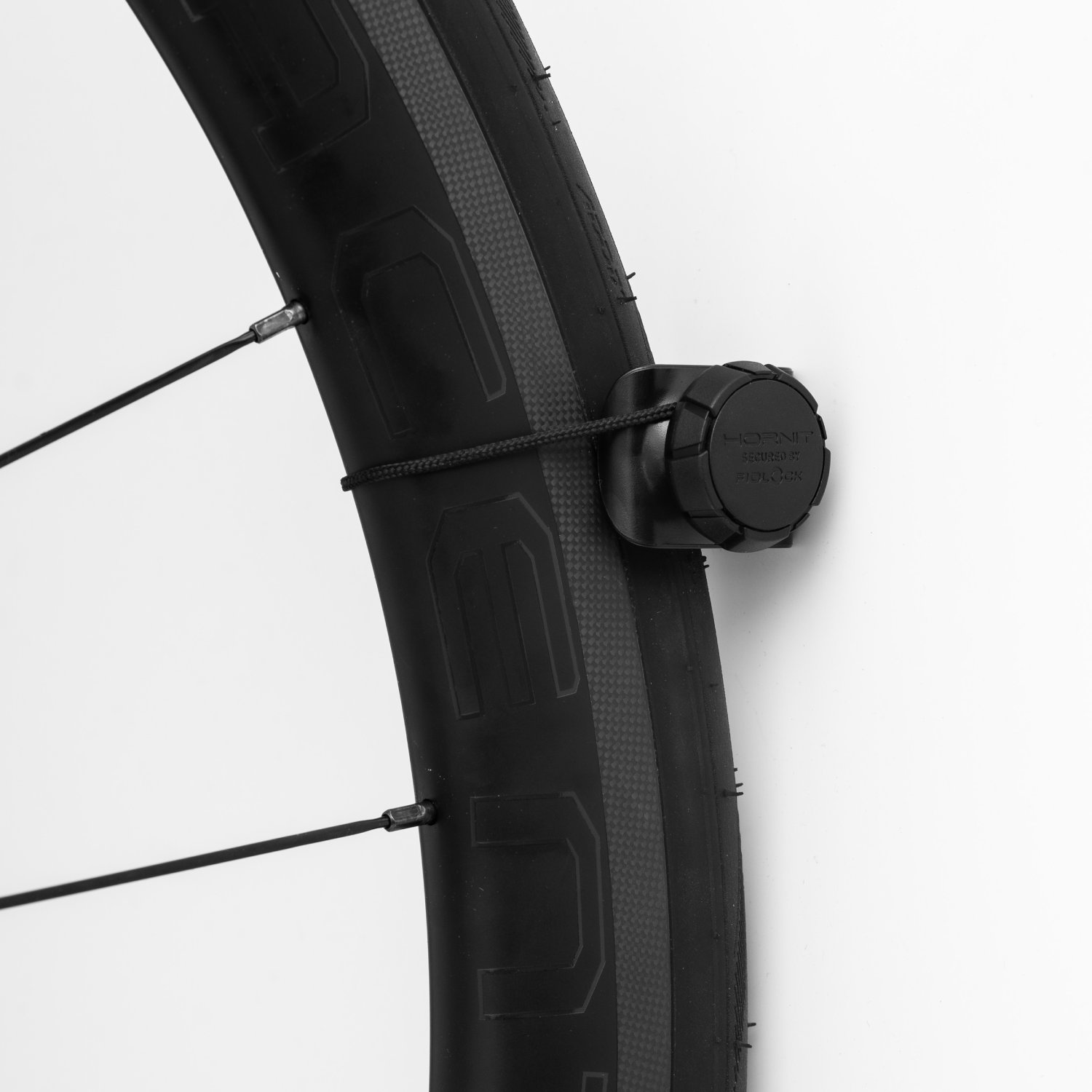 Een fietswiel met een zwarte sensor aan de spaken bevestigd. De band heeft tekst.