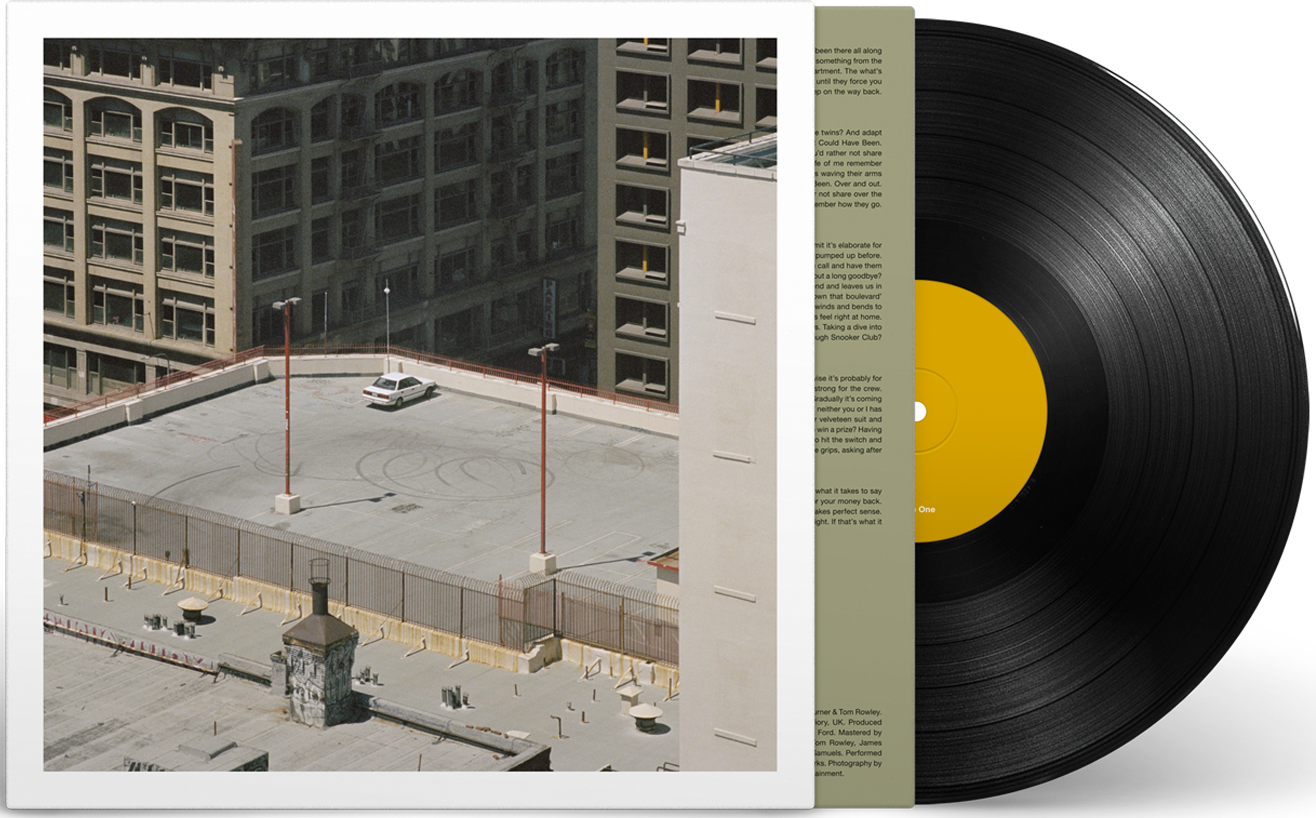 Vinil album borító városi épületekkel és autóval.