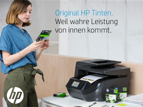 Frau hält HP-Druckerpatronen, mit Drucker und weiteren Patronen auf dem Tisch.