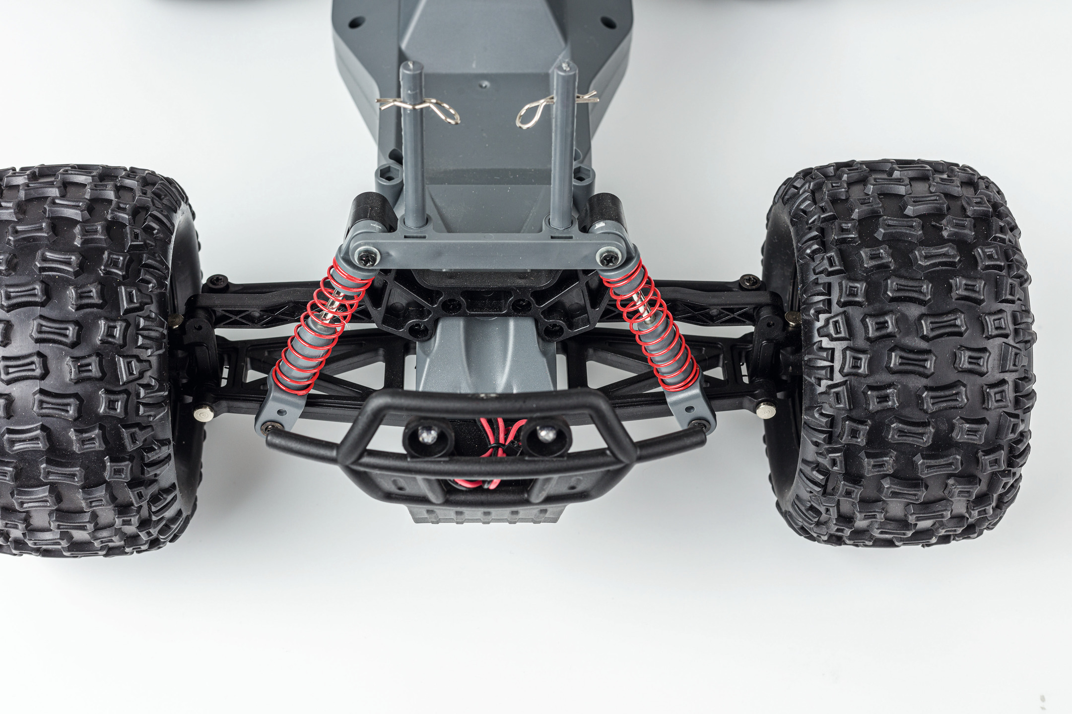 Nahaufnahme eines grauen RC-Auto-Chassis. Rote Stoßdämpfer, Reifen und Rahmen sichtbar.